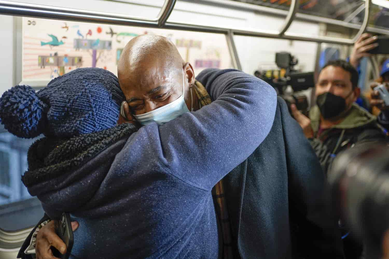 El alcalde de la ciudad de Nueva York, Eric Adams, abraza a la pasajera Pauline Munemya mientras viaja en el metro hacia el Ayuntamiento en su primer día en el cargo en Nueva York, el sábado 1 de enero de 2022.
