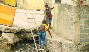 En Pantoja, la gente cruza sobre la basura de una ca&ntilde;ada por falta de un puente