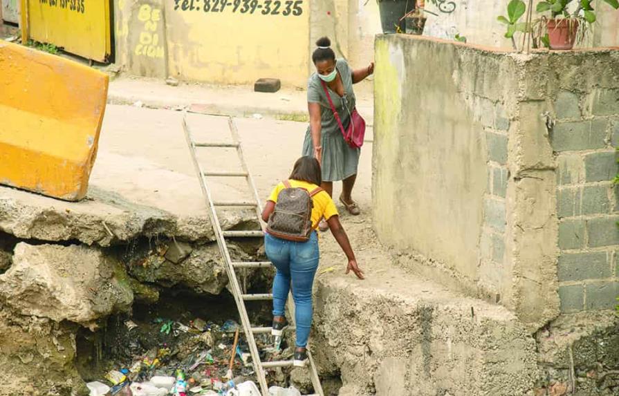 En Pantoja, la gente cruza sobre la basura de una cañada por falta de un puente