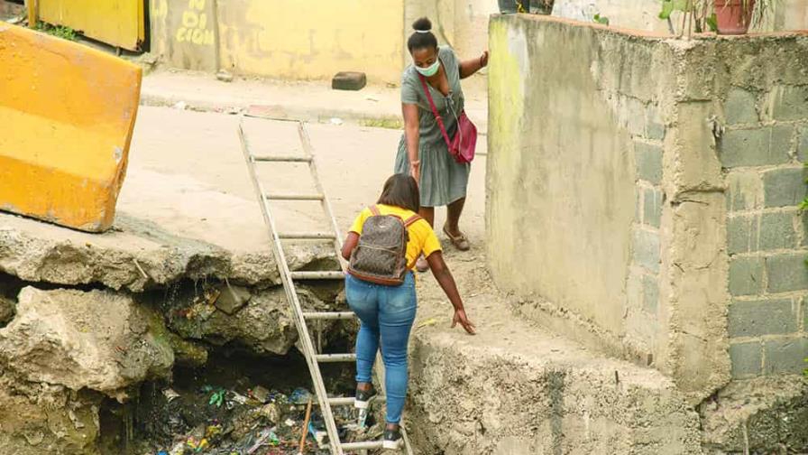 En Pantoja, la gente cruza sobre la basura de una cañada por falta de un puente