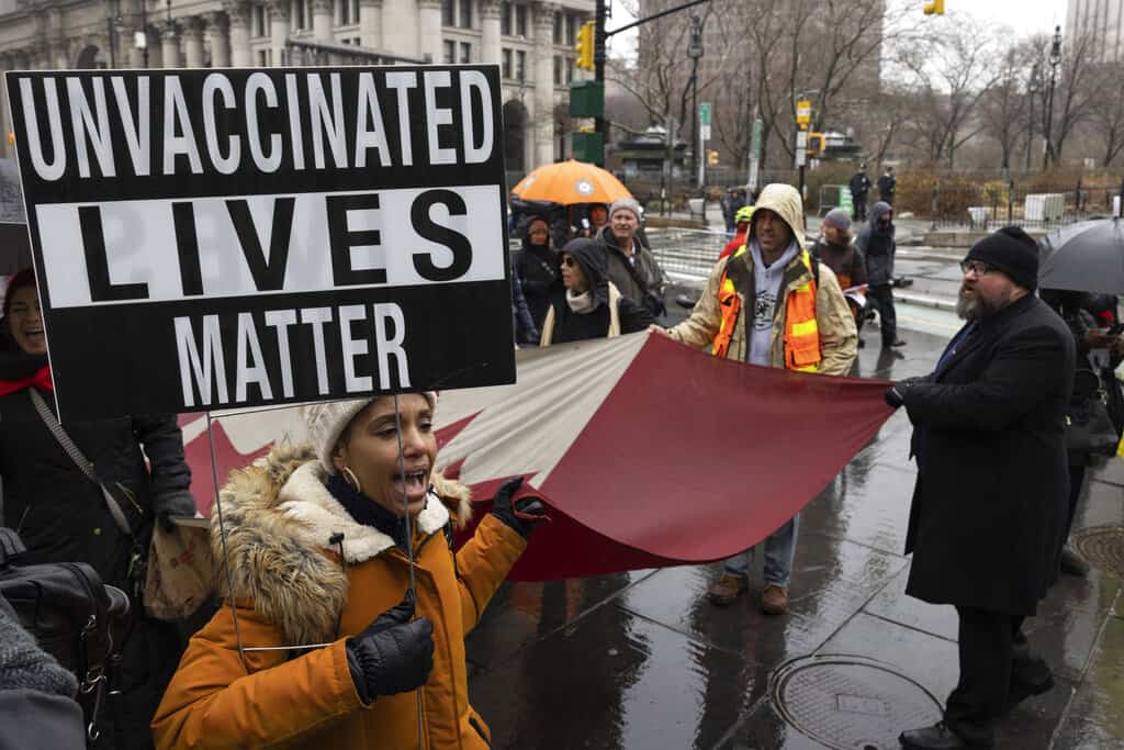 ARCHIVO - Una persona sostiene un cartel durante la protesta contra el mandato de vacunas antes de la posible terminación de los empleados de la ciudad de Nueva York debido a su estado de vacunación, el lunes 7 de febrero de 2022, en Nueva York. Varios miles de trabajadores públicos de la ciudad de Nueva York podrían perder sus trabajos el viernes 11 de febrero si no demuestran que han cumplido con el mandato de la ciudad que exige que reciban al menos dos inyecciones de la vacuna COVID-19.