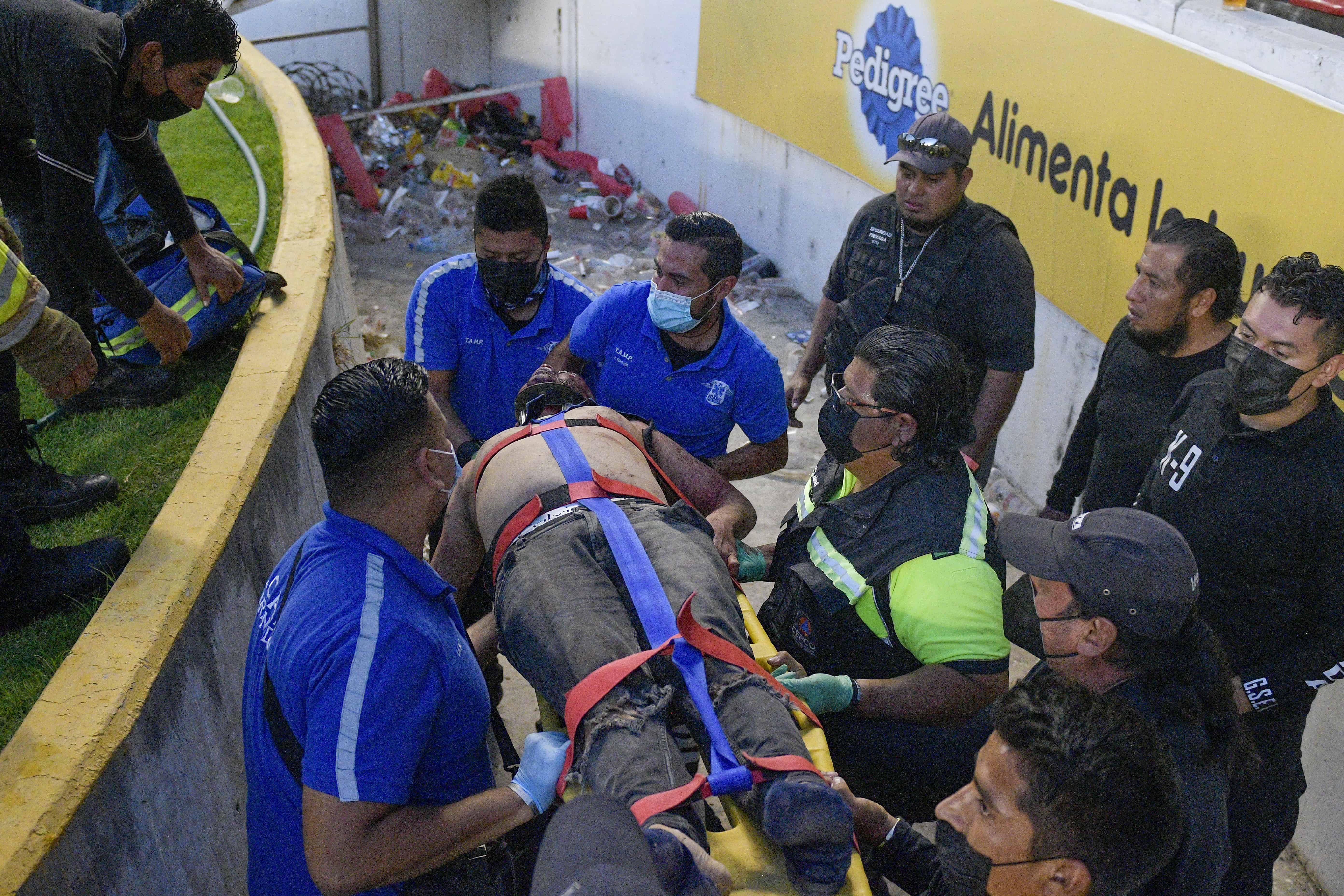 Un individuo es evacuado tras una riña de aficionados del Querétaro y del Atlas durante un partido de la Liga MX, el sábado 5 de marzo de 2022, en el Estadio Corregidora de Querétaro.