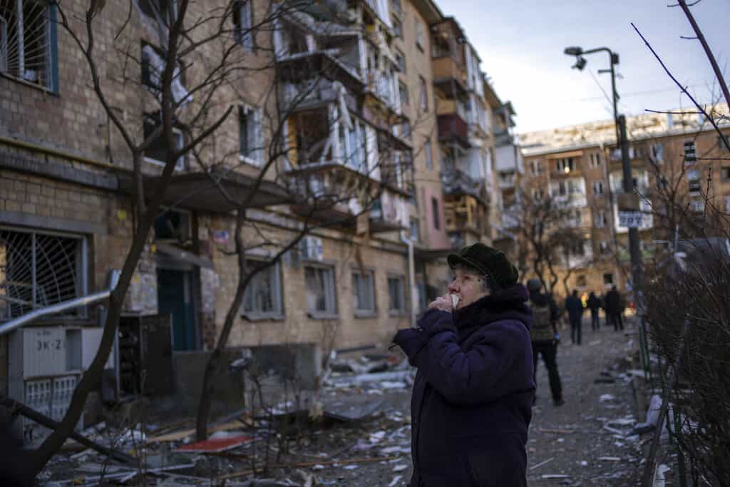 Una mujer mira los edificios residenciales dañados por una bomba en Kiev, Ucrania, el viernes 18 de marzo de 2022. Las fuerzas rusas intensificaron su asalto a las ciudades ucranianas el viernes, con nuevos ataques con misiles y bombardeos en los bordes de la capital Kiev y la ciudad occidental de Lviv.