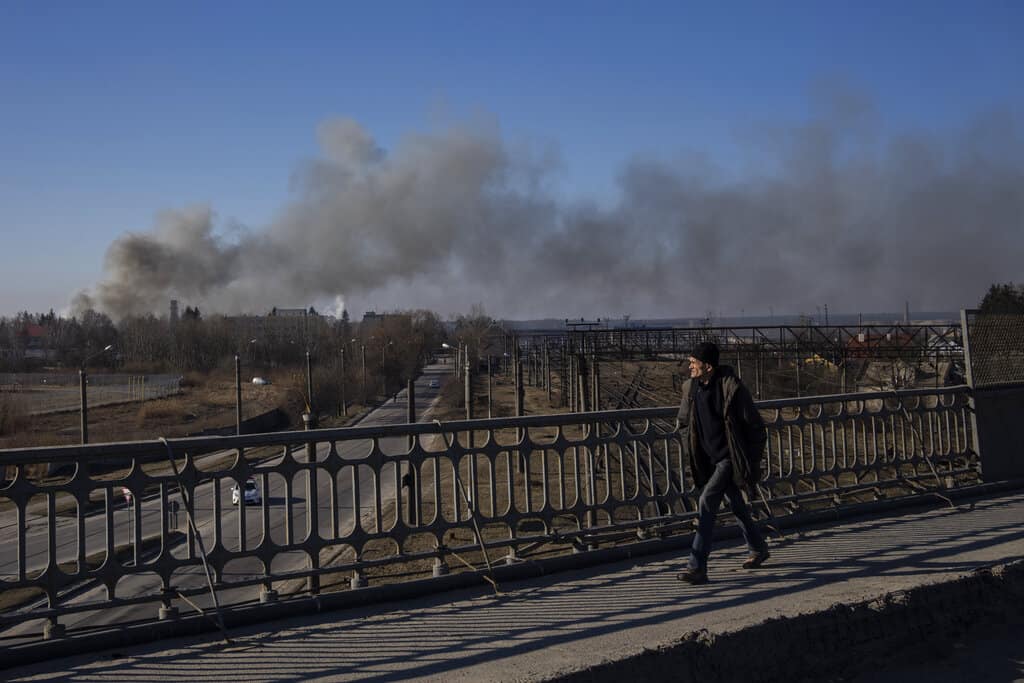 Un peatón mira una nube de humo que se eleva después de una explosión en Lviv, Ucrania occidental, el viernes 18 de marzo de 2022. El alcalde de Lviv dice que los misiles impactaron cerca del aeropuerto de la ciudad el viernes temprano.