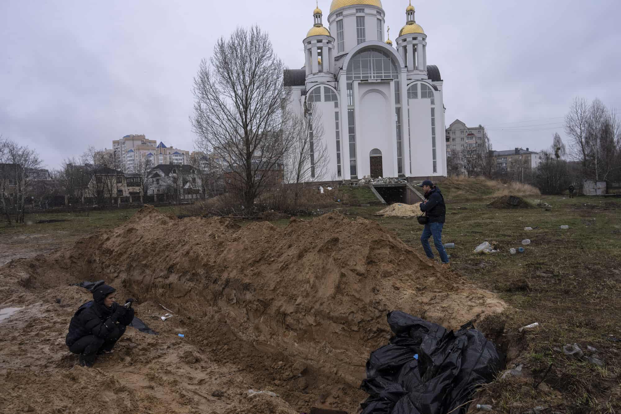 Periodistas toman fotografías junto a una fosa común en Bucha, en las afueras de Kiev, Ucrania, el domingo 3 de abril de 2022