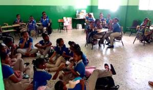 Por falta de butacas los estudiantes toman clases en el suelo