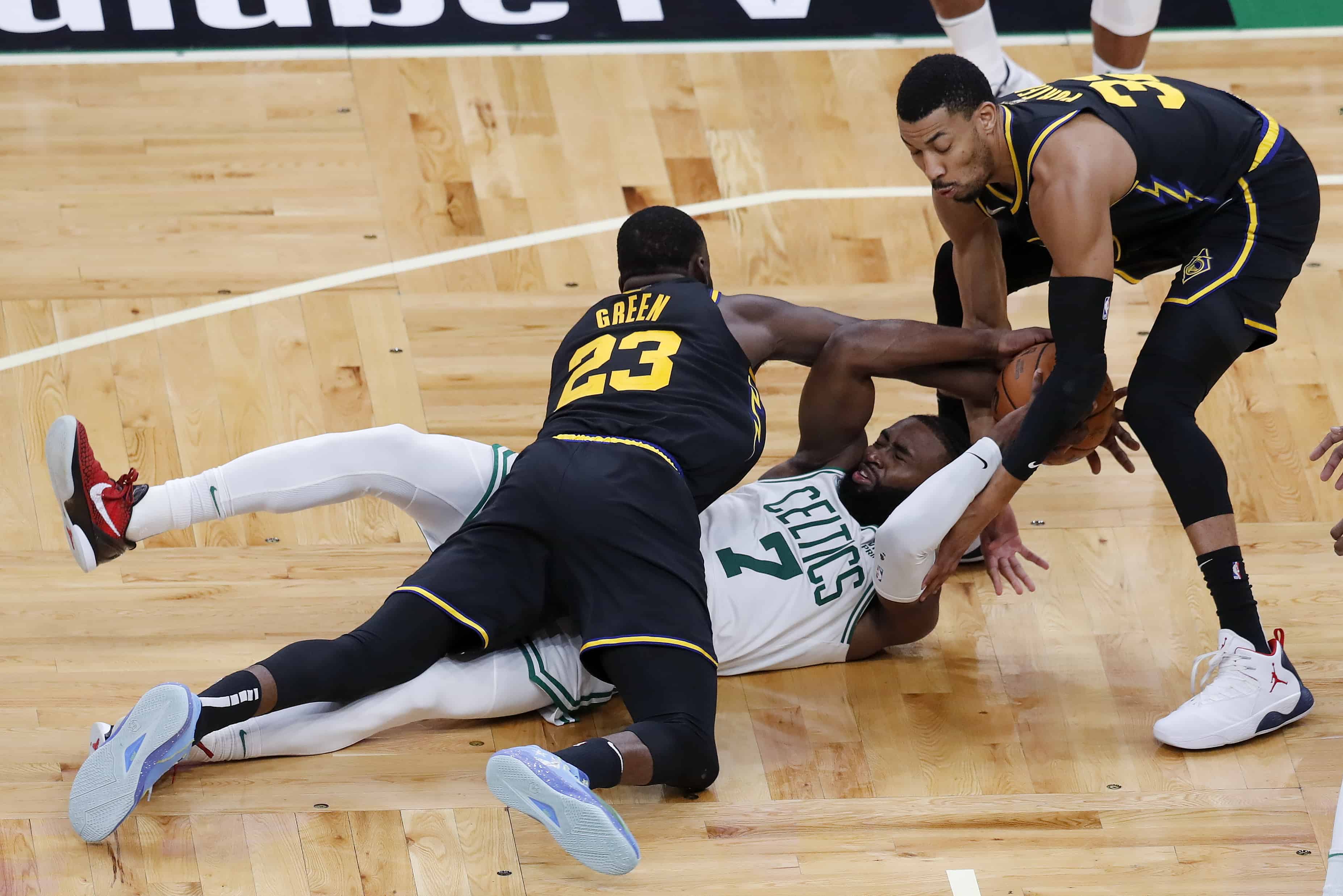 El escolta de los Boston Celtics, Jaylen Brown (7), lucha por un balón suelto contra el alero de los Golden State Warriors, Draymond Green (23) y el alero Otto Porter Jr. (32), durante la segunda mitad del Juego 3 de las Finales de la NBA de baloncesto, el miércoles 8 de junio de 2022 , en Boston.