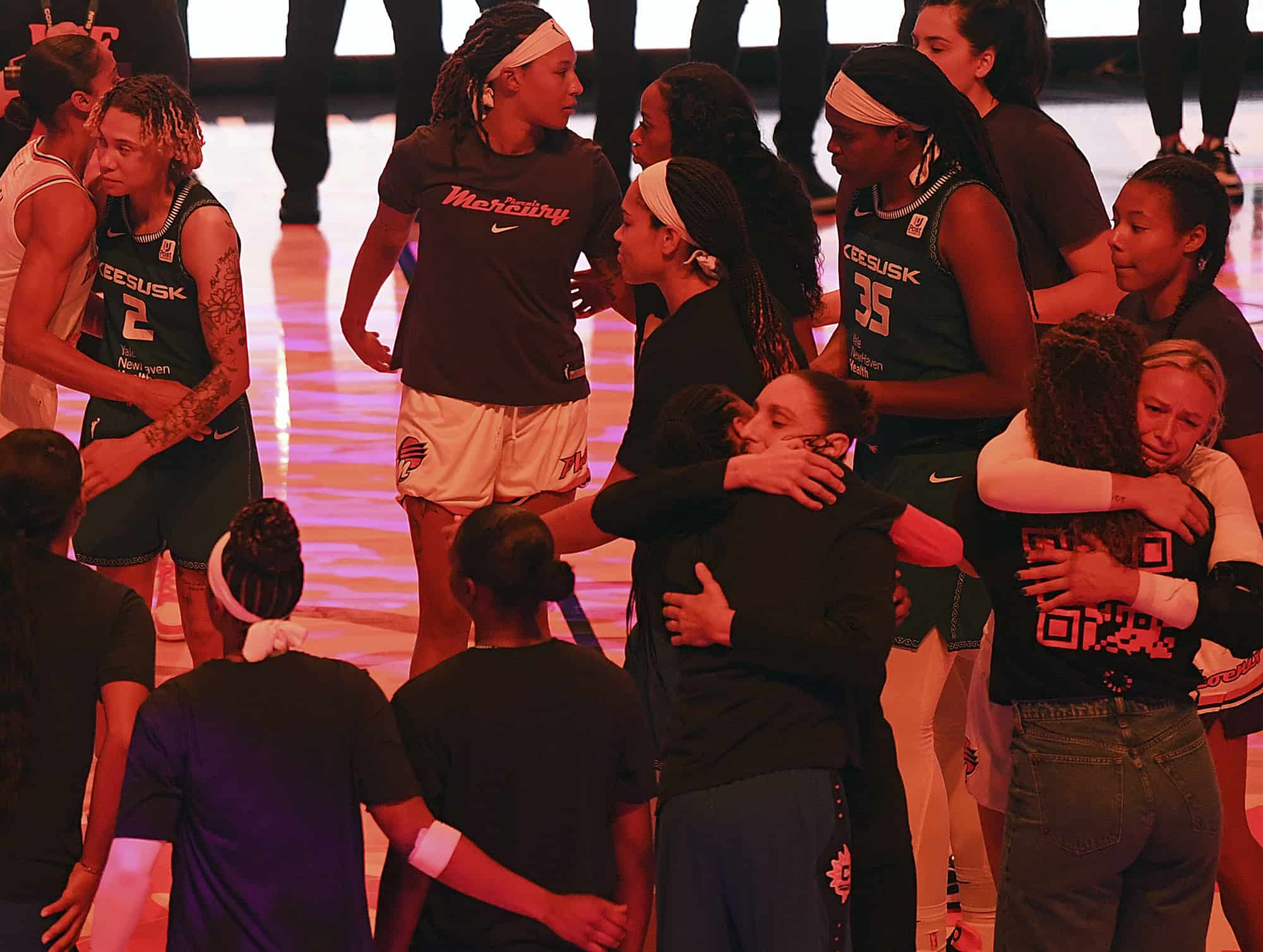 Los jugadores de Connecticut Sun y Phoenix Mercury se abrazan luego de un momento de silencio por la centro de Phoenix Mercury, Brittney Griner, antes de un partido de baloncesto de la WNBA el jueves 4 de agosto de 2022 en Uncasville, Connecticut. Griner fue condenado el jueves en Rusia por posesión y contrabando de drogas y fue condenado a nueve años tras las rejas. 