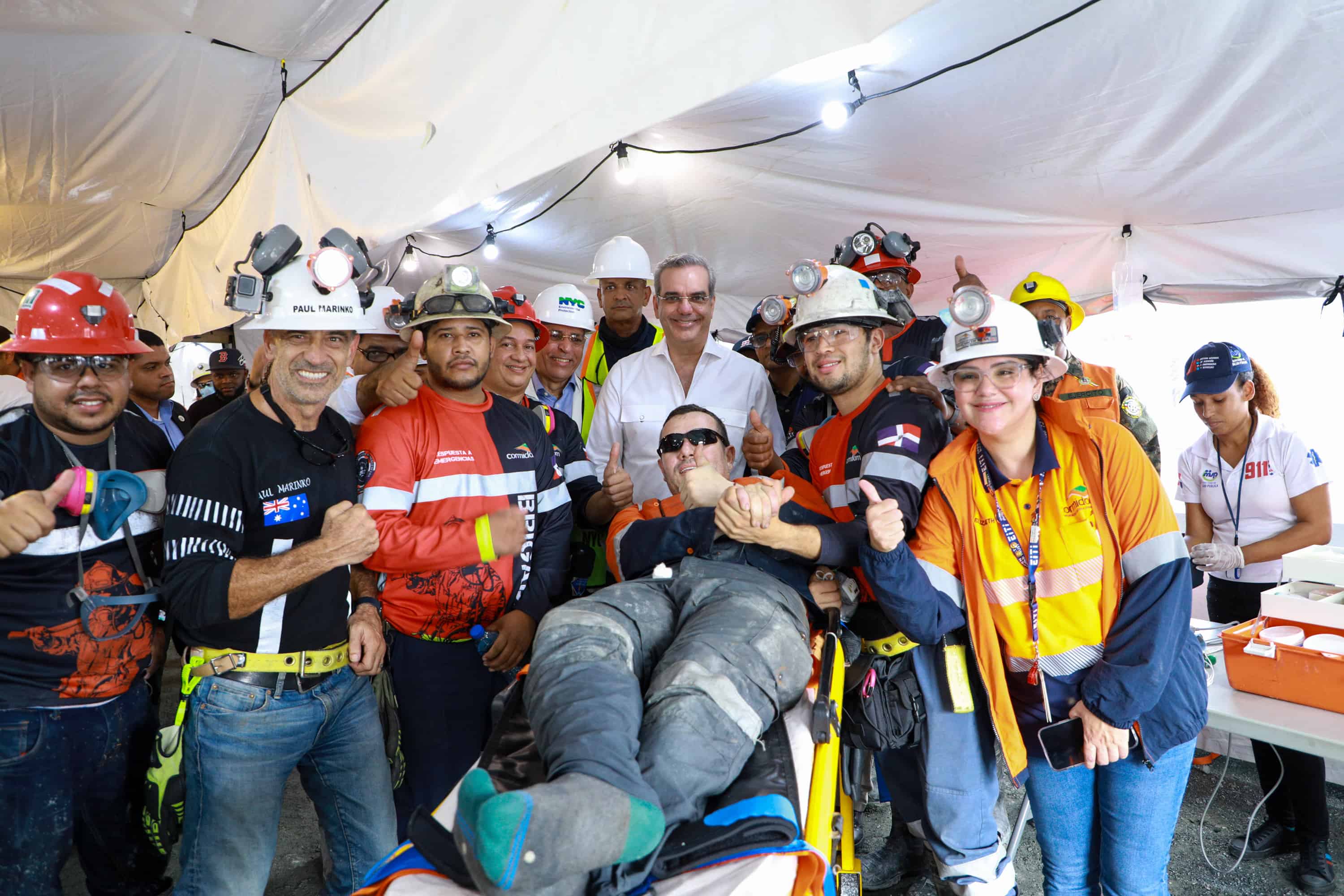 El minero Carlos Yépes Ospina posa junto al presidente Luis Abinader y parte del equipo que trabajó en el rescate que lo liberó del encierro que sufrió en una mina del Cerro Maimón
