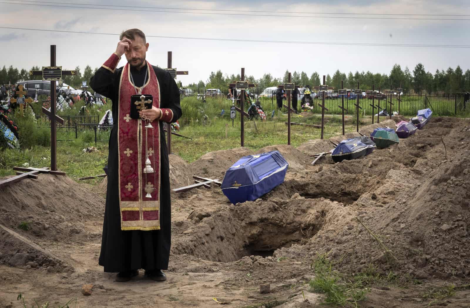 Archivo - El sacerdote ortodoxo Padre Andriy reza por los civiles no identificados asesinados por las tropas rusas durante la ocupación rusa en Bucha, en las afueras de Kyiv, Ucrania, el 11 de agosto de 2022.