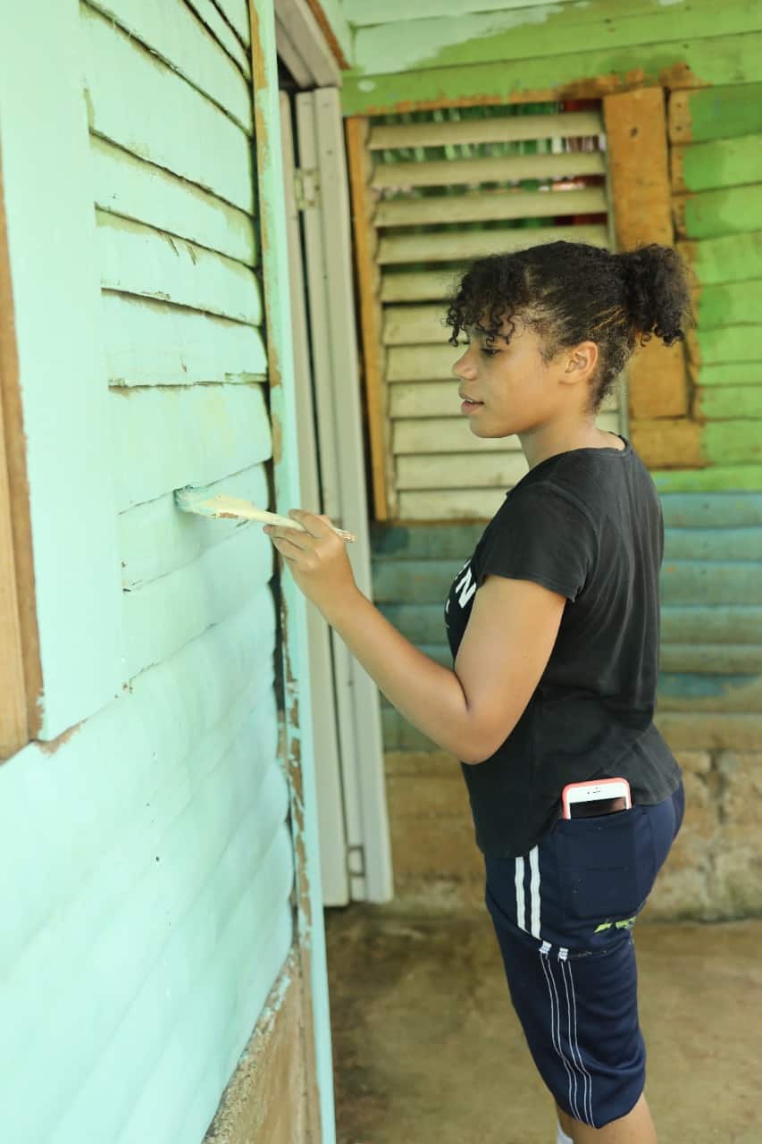 Una joven misionera pinta una casa intervenida en Guanuma.