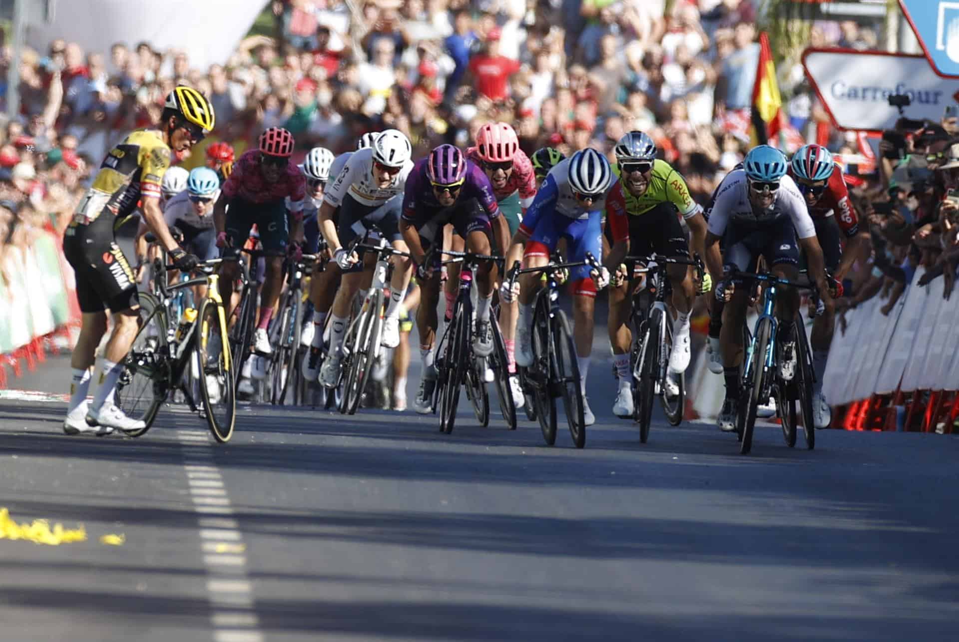 El ciclista esloveno Primoz Roglic (i), del equipo Jumbo Visma, se vuelve a montar en la bicicleta tras sufrir una caída a pocos metros de la línea de meta de la decimosexta etapa de la Vuelta a España, entre Sanlúcar de Barrameda y Tomares sobre 189,4 kilómetros, este martes.