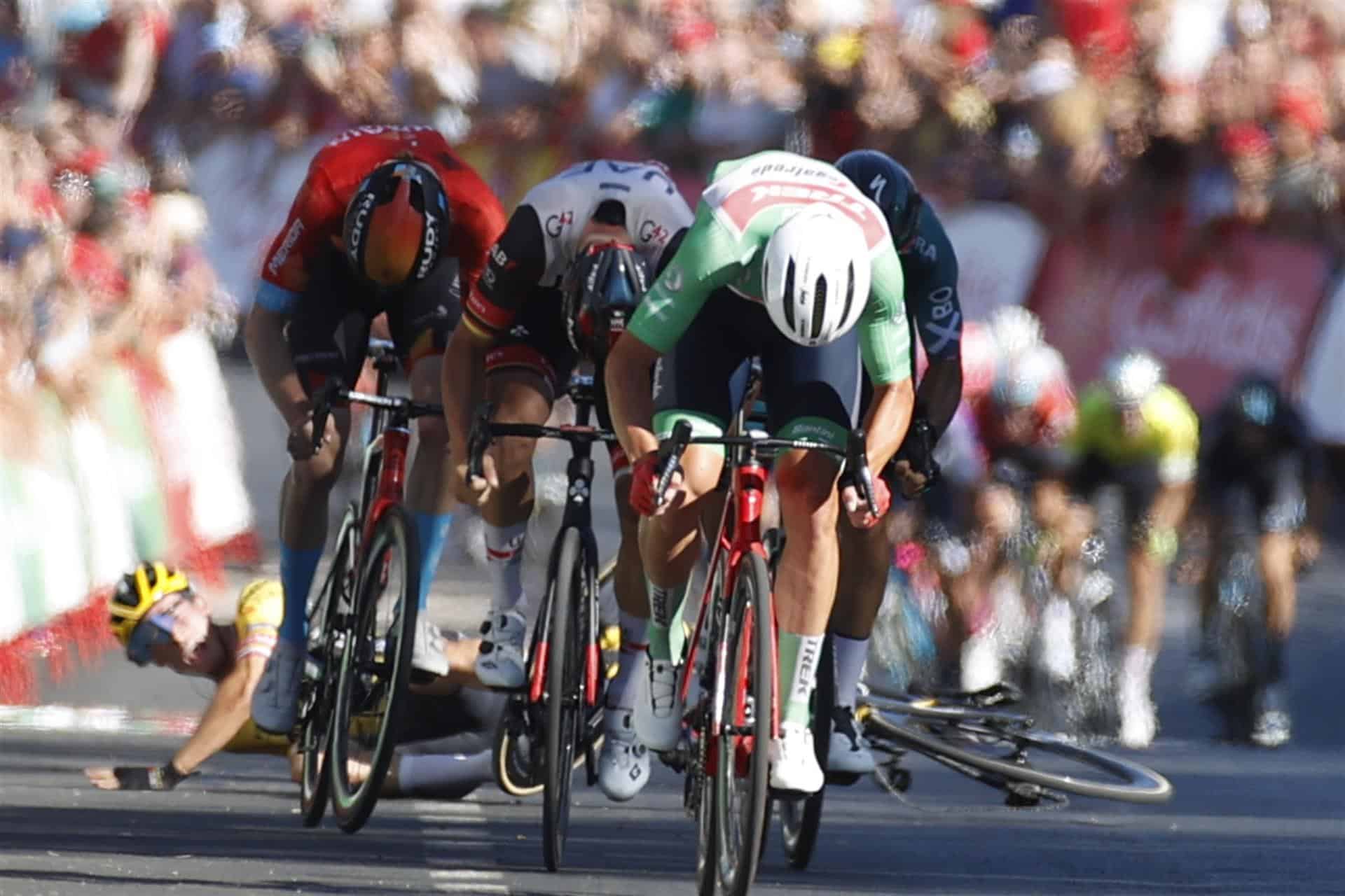 El ciclista esloveno Primoz Roglic (i), del equipo Jumbo Visma, sufre una caída a pocos metros de la línea de meta al tiempo que el ciclista danés Mads Pedersen (c), del equipo Trek-Segafredo y líder de la regularidad, se proclama vencedor de la decimosexta etapa de la Vuelta a España, entre Sanlúcar de Barrameda y Tomares sobre 189,4 kilómetros, este martes.