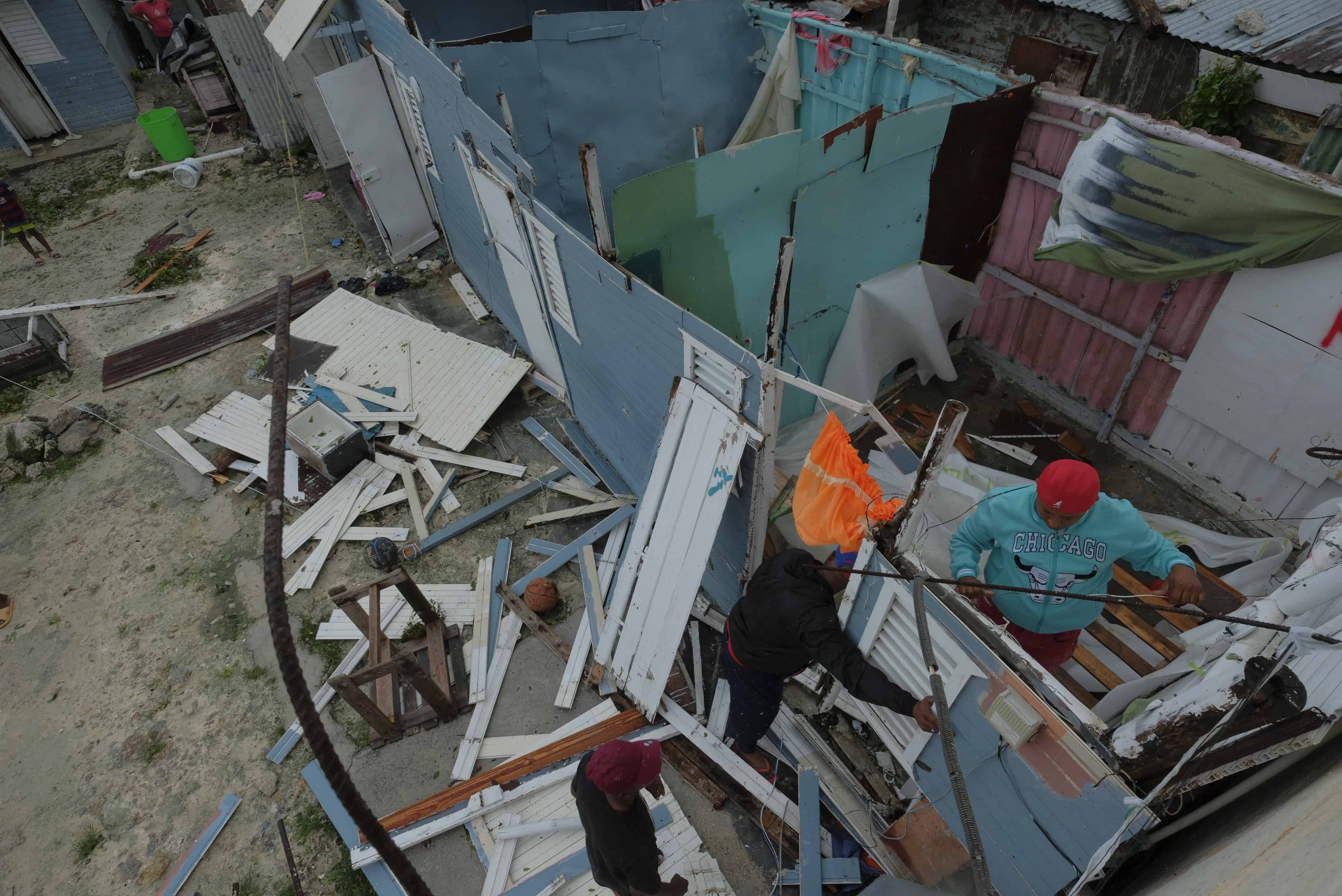 Tres hombres buscan entre los restos de viviendas que perdieron su techo tras el paso del huracán Fiona por Nagua.