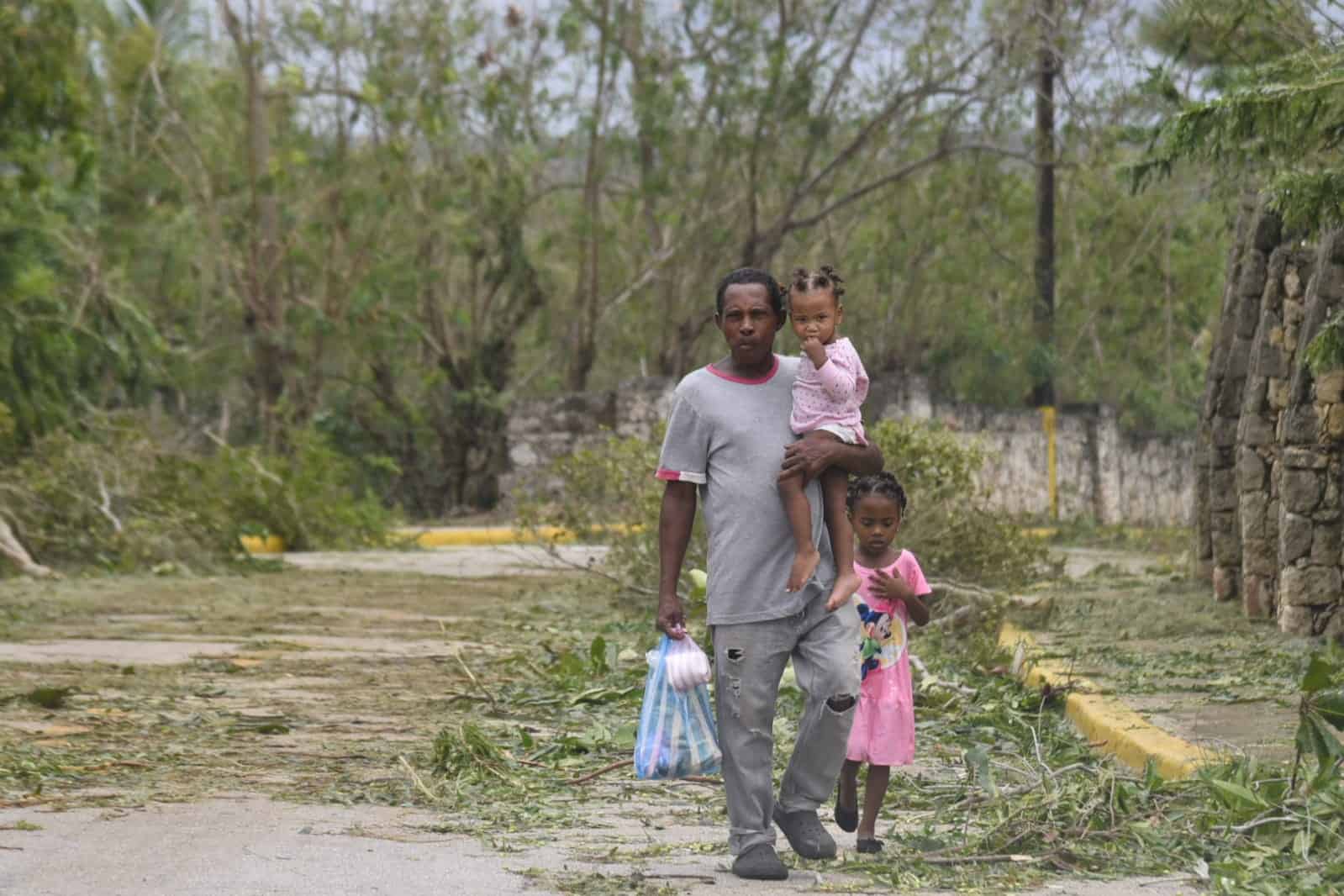 Un hombre y sus hijas regresan a pie tras adquirir alimentos en un sector cercano a Boca de Yuma.