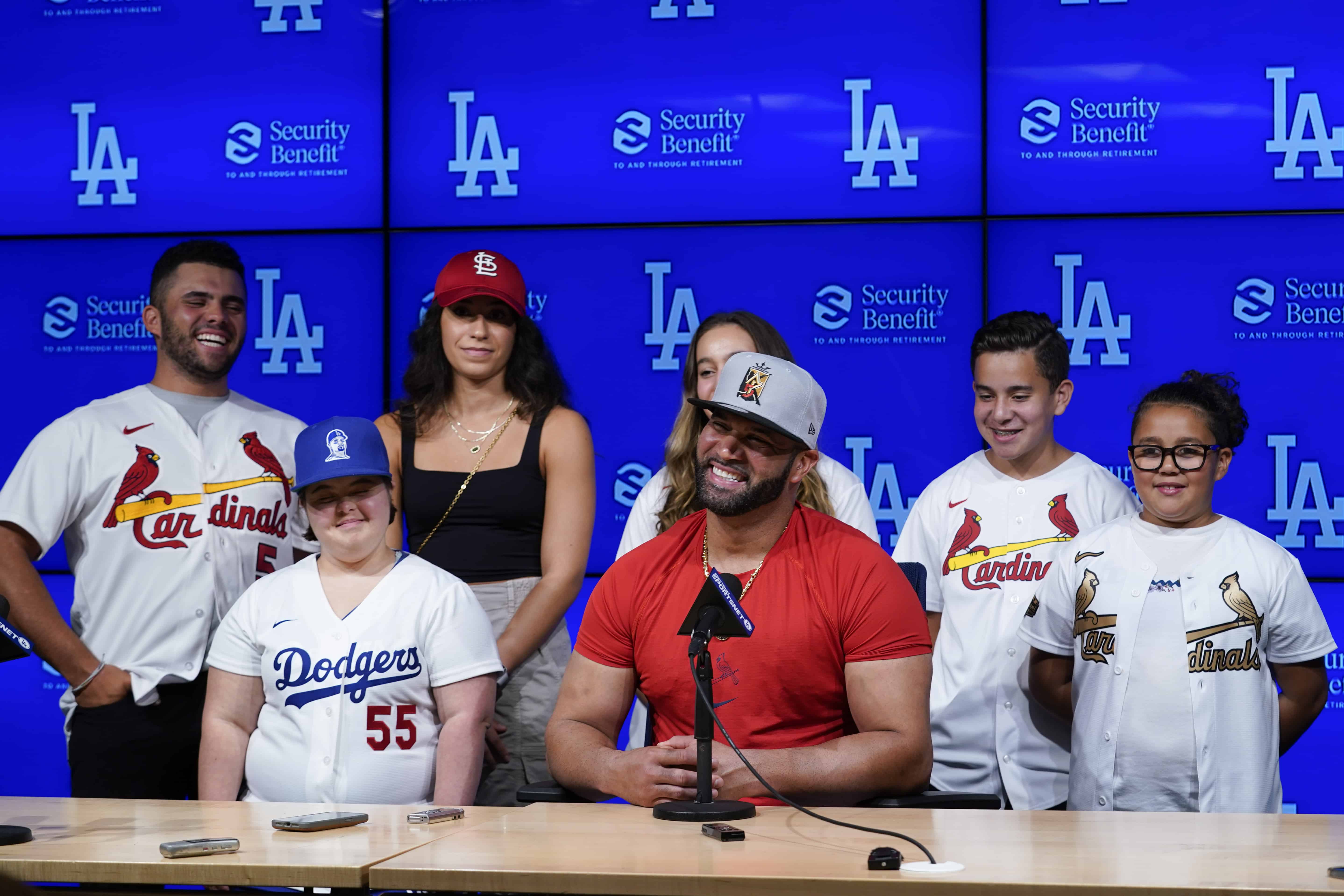 El bateador designado de los Cardenales de San Luis, Albert Pujols, en el centro, está rodeado por su familia mientras habla con los periodistas después de un partido de béisbol contra los Dodgers de Los Ángeles en Los Ángeles, el viernes 23 de septiembre de 2022. Pujols conectó su jonrón 700 durante el cuarto inning. 