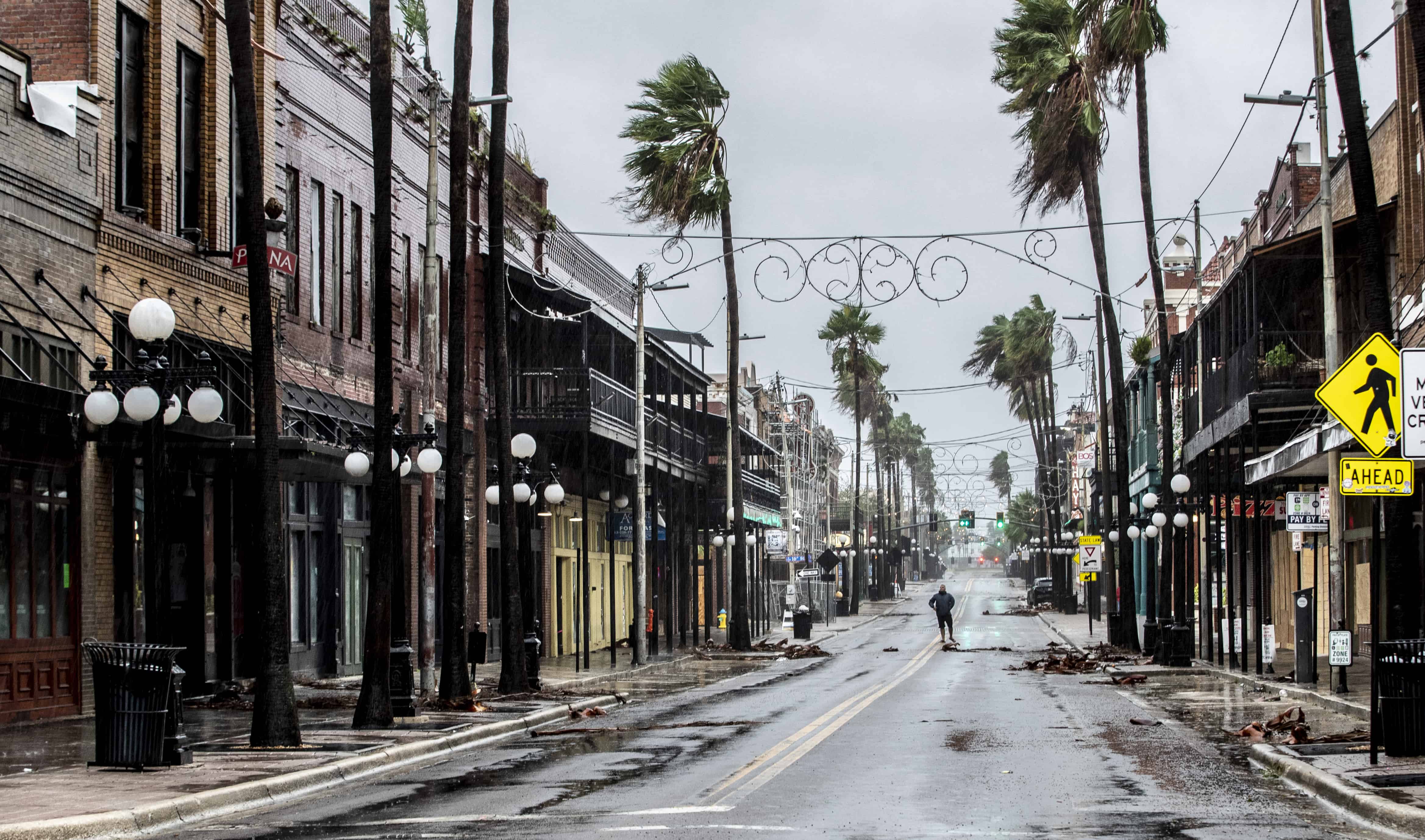 Un hombre se para en el medio de 7th Street en Ybor City en las calles empapadas por la lluvia, unas horas antes de que los fuertes vientos del huracán Ian azotaran Tampa, Florida, el miércoles 28 de septiembre de 2022.