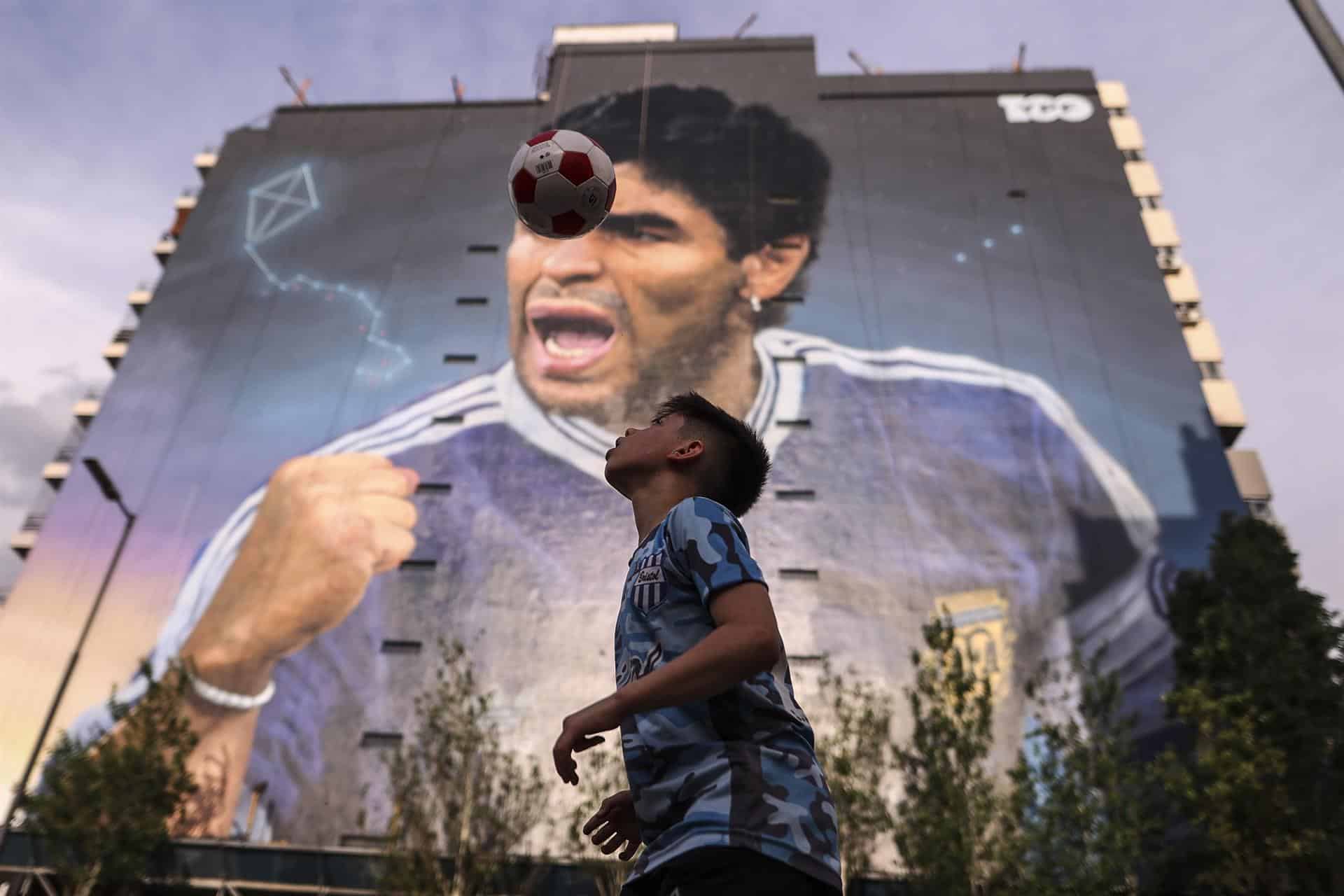 Niños juegan fútbol cerca al mural en honor a Diego Armando Maradona realizado por Martín Ron, el 28 de octubre de 2022 en Buenos Aires (Argentina). La muerte de Diego Armando Maradona propició infinidad de homenajes por toda Argentina. 