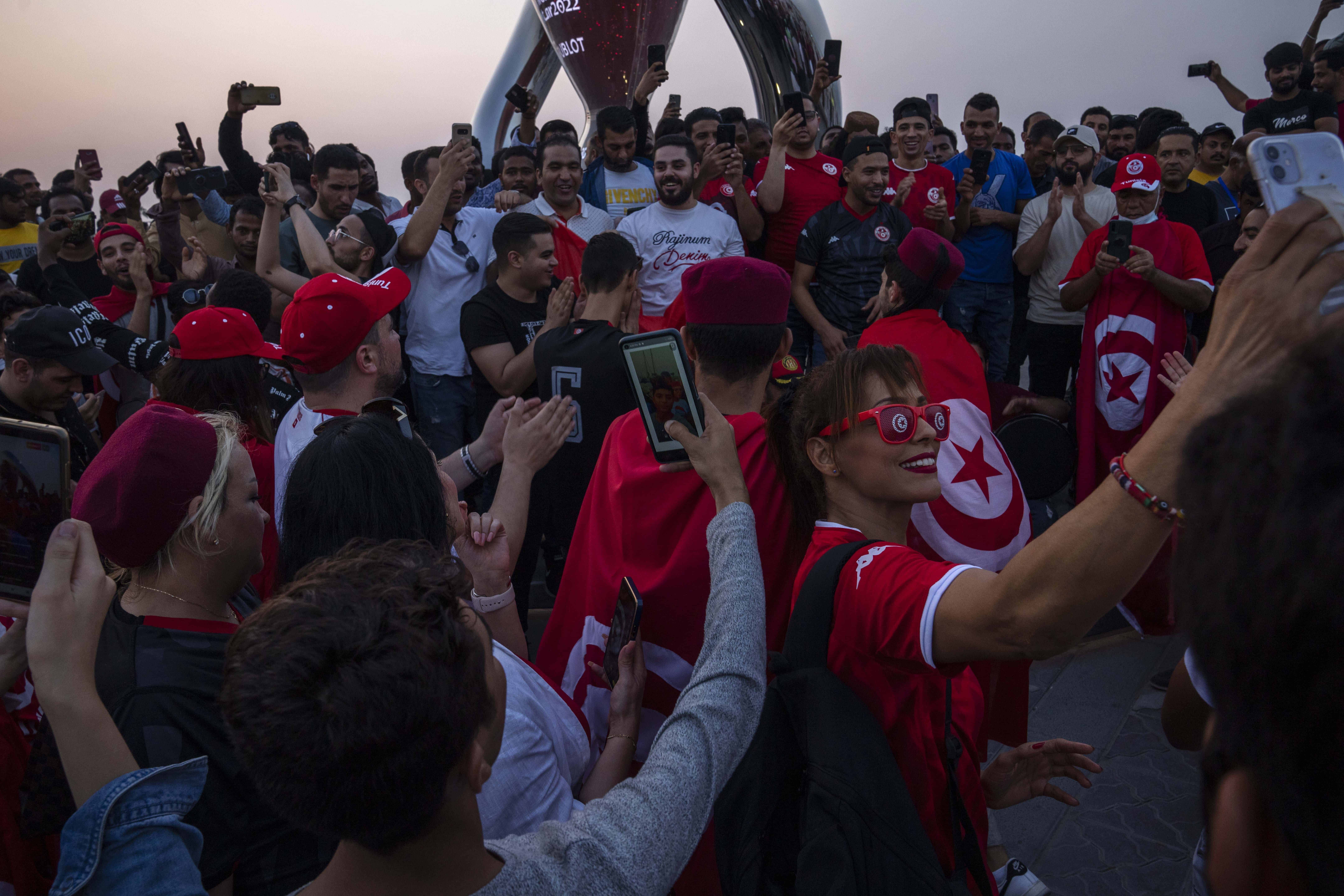 Aficionados de la selección de Túnez se sacan fotos frente al reloj con la cuenta regresiva del Mundial de Qatar 2022, en Doha, el viernes 21 de octubre de 2022. <br>