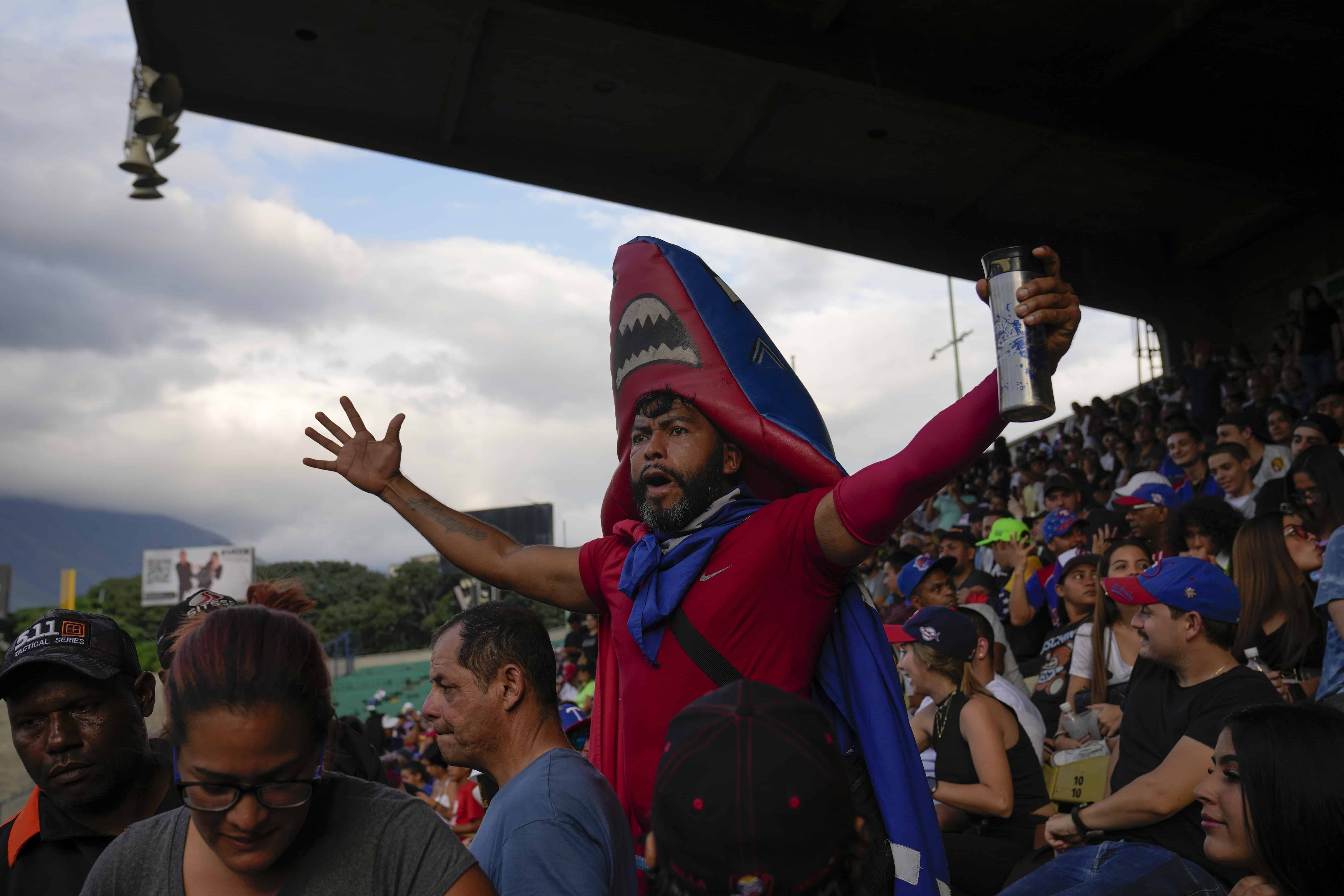 Un fanático de Tiburones de la Guaira anima durante un partido de béisbol entre Leones del Caracas y Tiburones de la Guaira en la temporada de béisbol de la Liga Invernal de Venezuela en Caracas, Venezuela, el domingo 6 de noviembre de 2022.