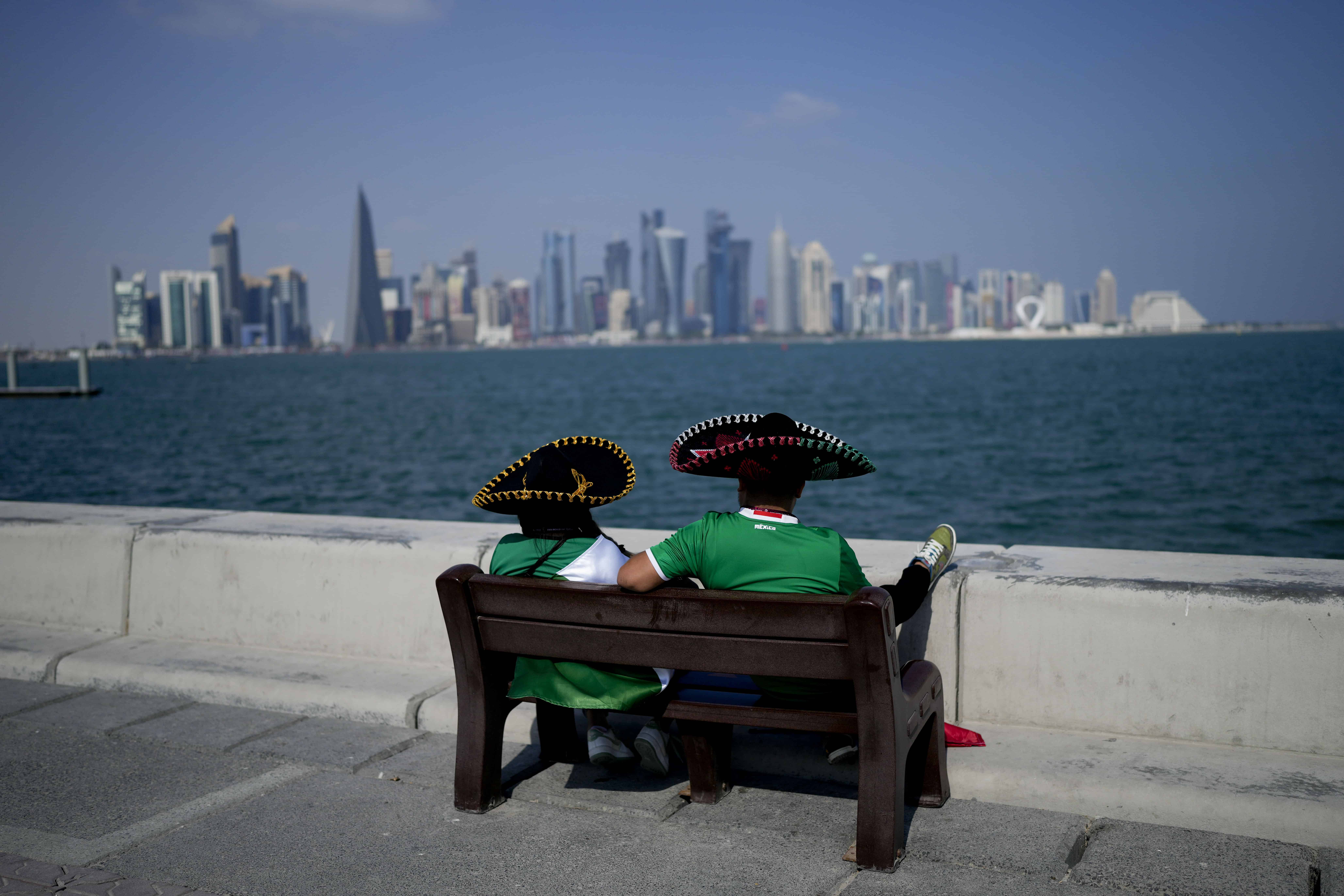 Dos aficionados mexicanos, tocados con el tradicional sombrero charro, sentados en un banco en el paseo marítimo de Doha, el 21 de noviembre de 2022.
