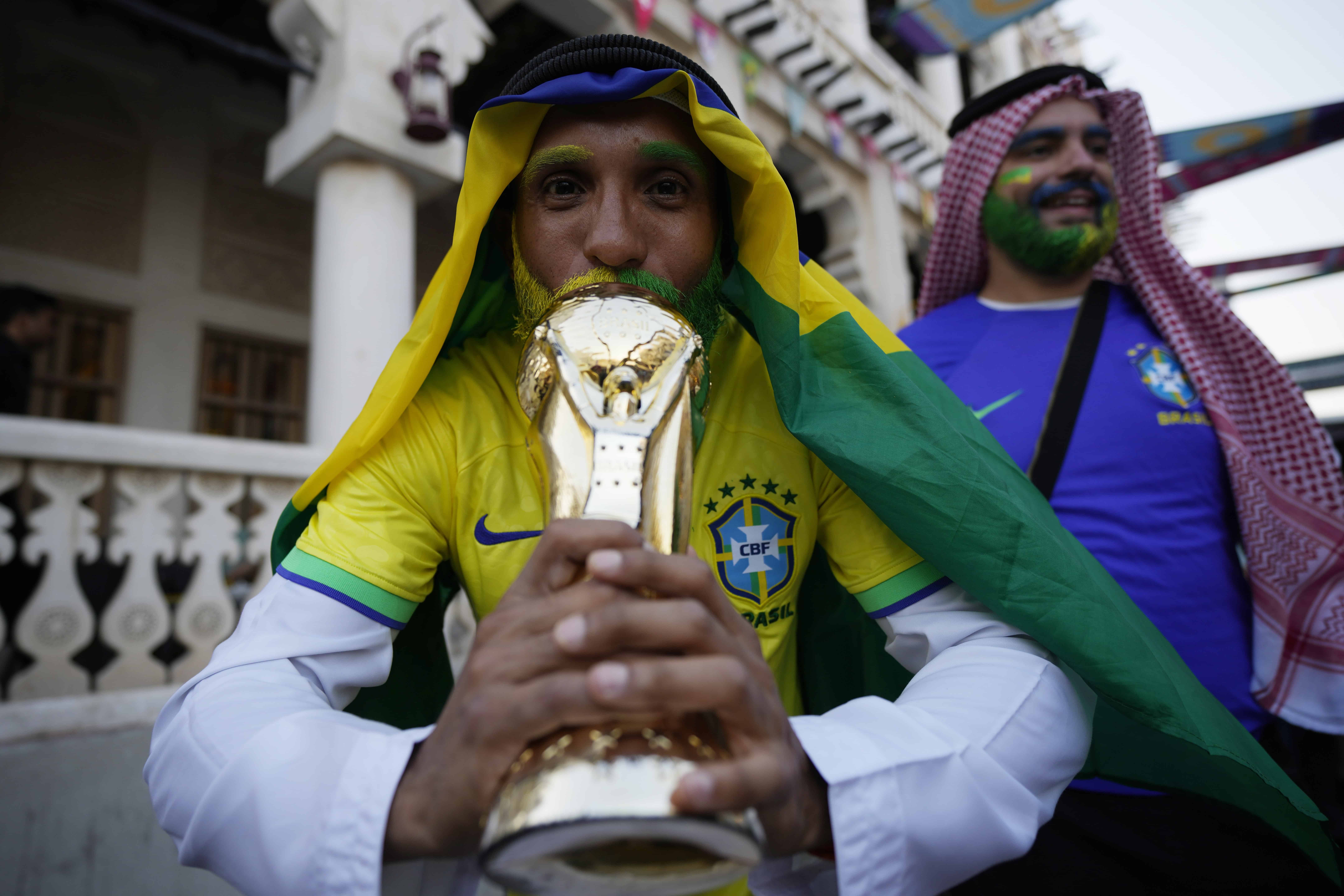 Un aficionado de Brasil besa la réplica del trofeo de la Copa del Mundo en el mercado Souq Waqif en Doha, Qatar, el viernes 25 de noviembre de 2022.