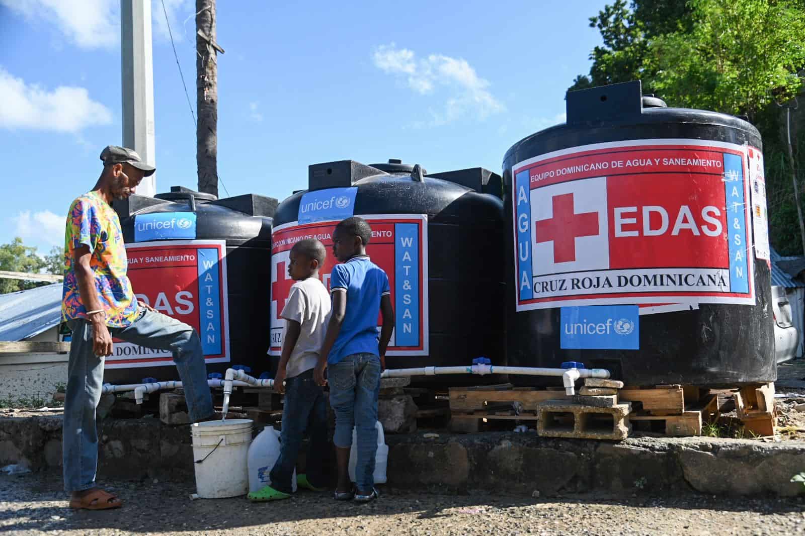 Un hombre y niños llenan de agua potable sus envases. 