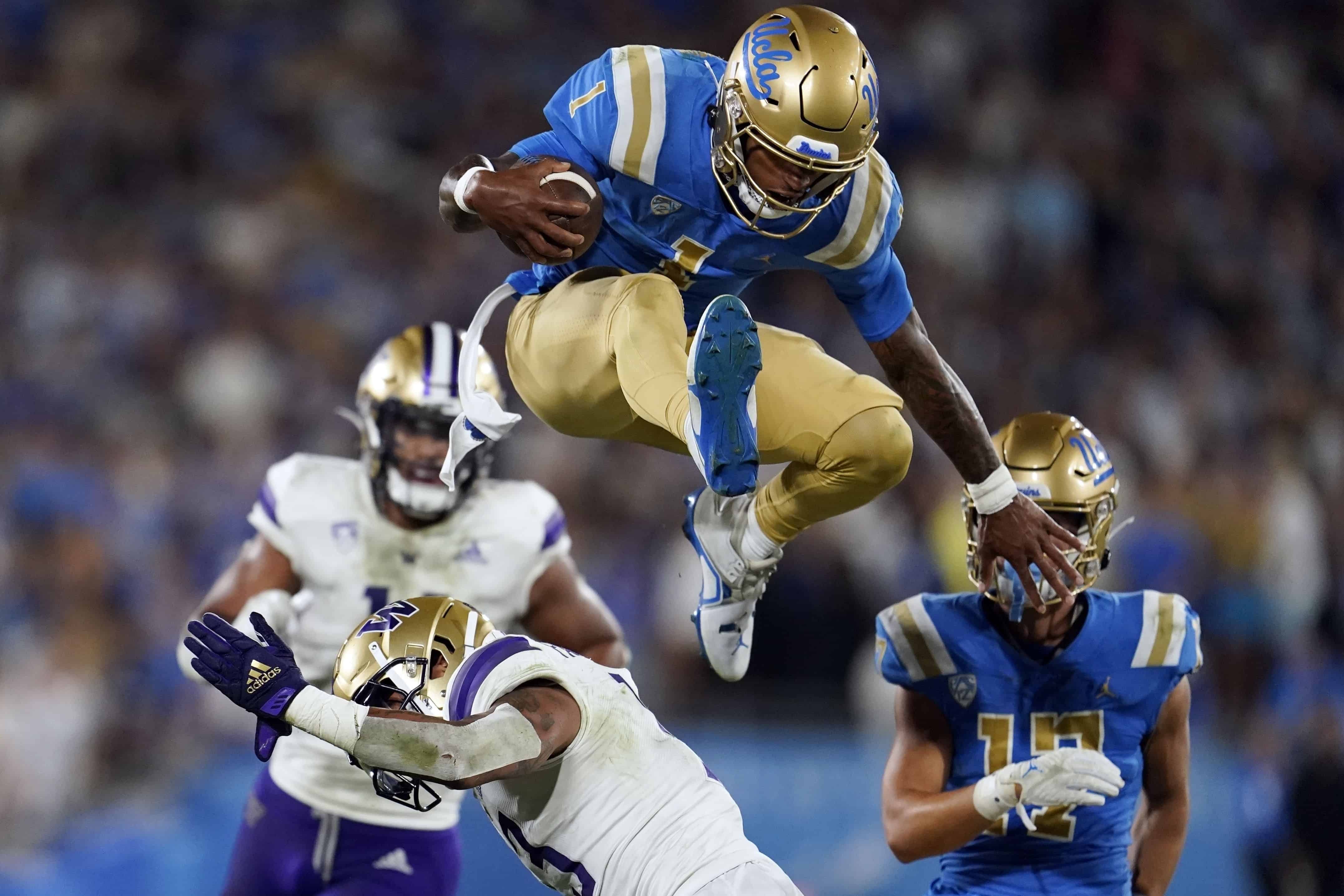 Dorian Thompson-Robinson, de UCLA, salta por encima de Kamren Fabiculanan, de Washington, durante un partido colegial, el 30 de septiembre de 2022, en Pasadena, California.<br>