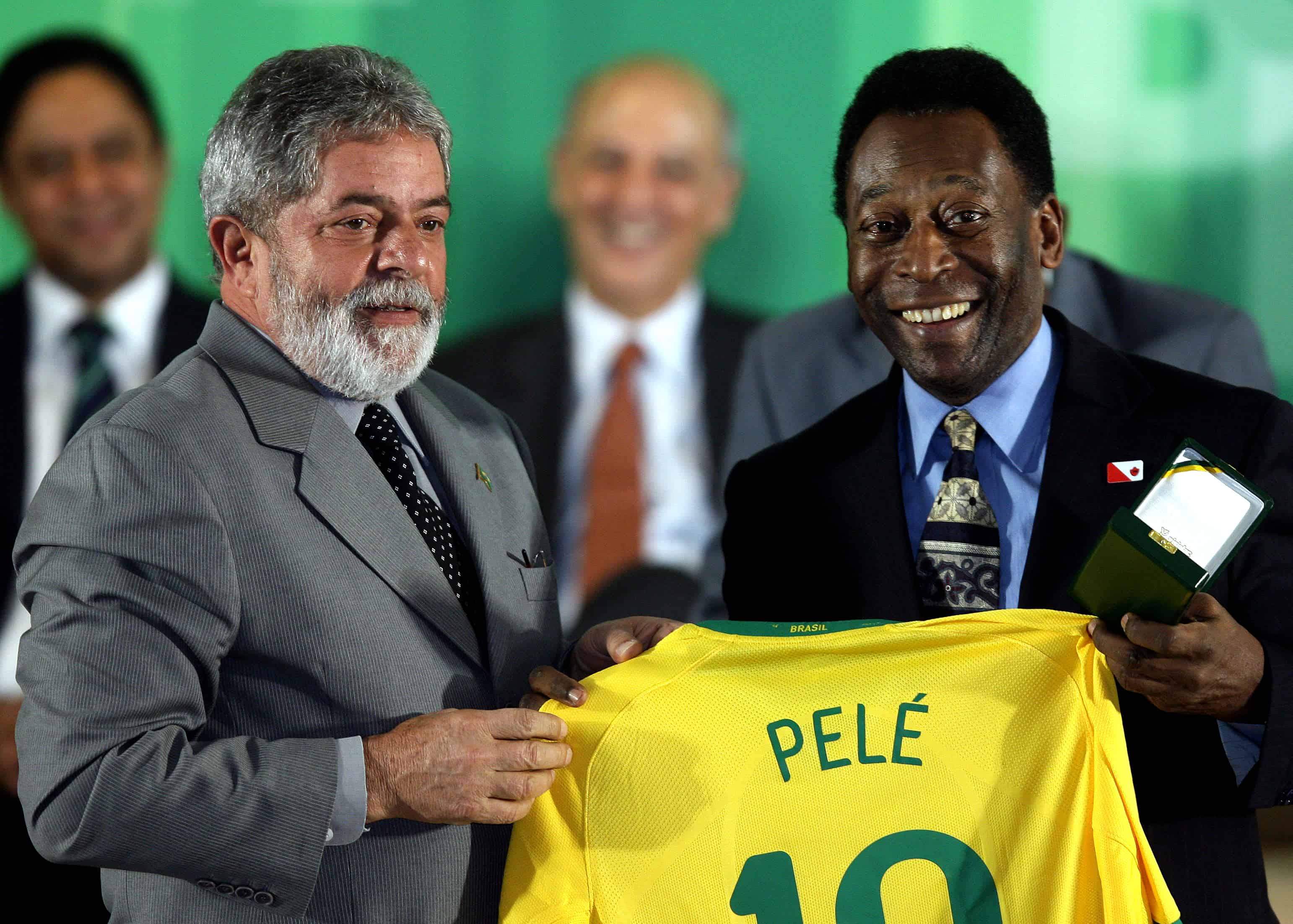 El presidente brasileño Luiz Inácio Lula da Silva (L) y la leyenda del fútbol brasileño Edson Arantes do Nacimento, conocido como Pelé, sostienen una camiseta durante una ceremonia para decorar a los ganadores de la Copa del Mundo de 1958, en la ceremonia de apertura de una exposición que celebra el 50 aniversario. de la primera victoria de Brasil en este torneo, en el palacio Planalto en Brasilia el 26 de junio de 2008.