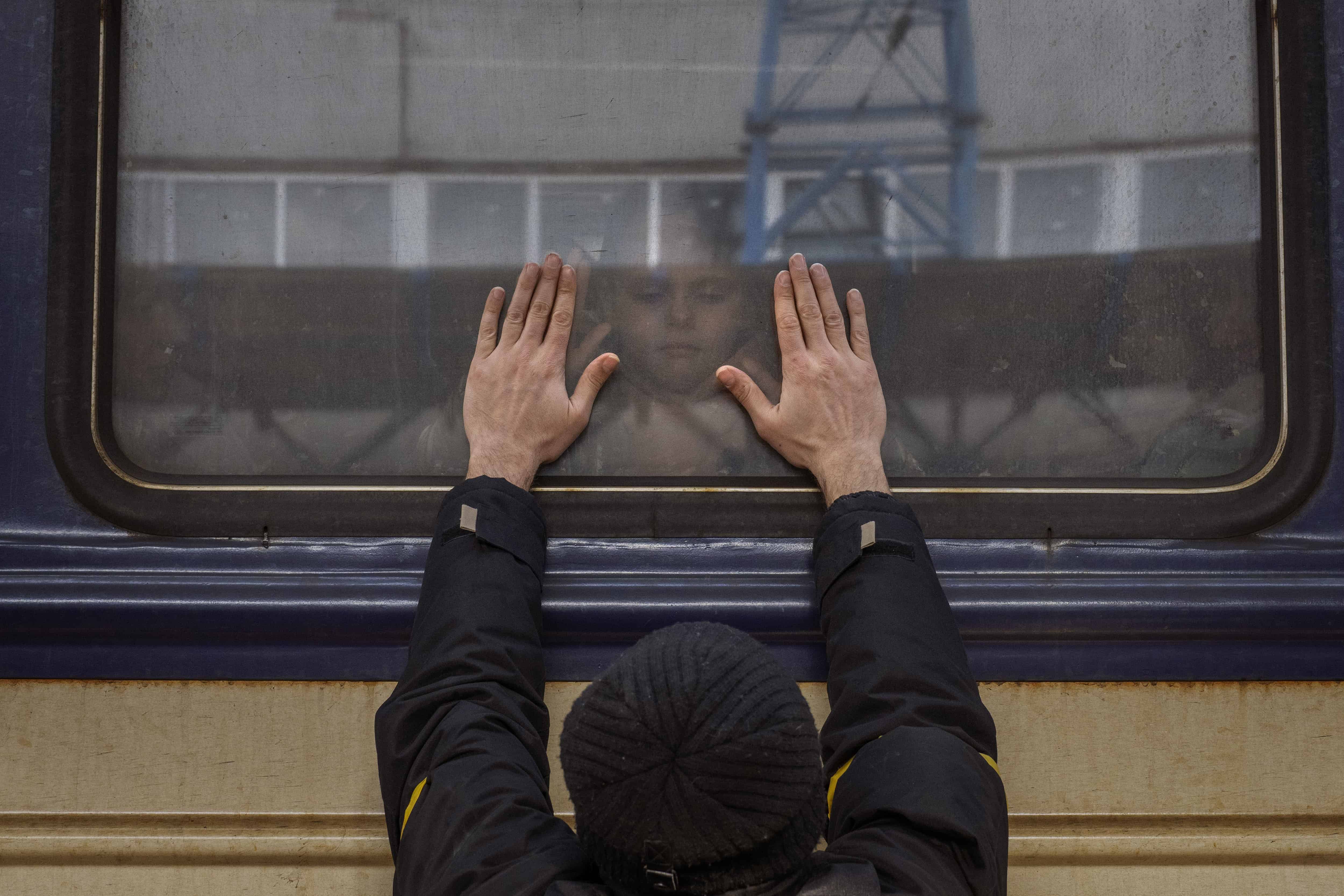 Aleksander, de 41 años, presiona sus palmas contra la ventana de un tren con destino a Leópolis mientras se despide de su hija Anna, de 5 años, en la estación ferroviaria de Kiev, Ucrania, el 4 de marzo de 2022.