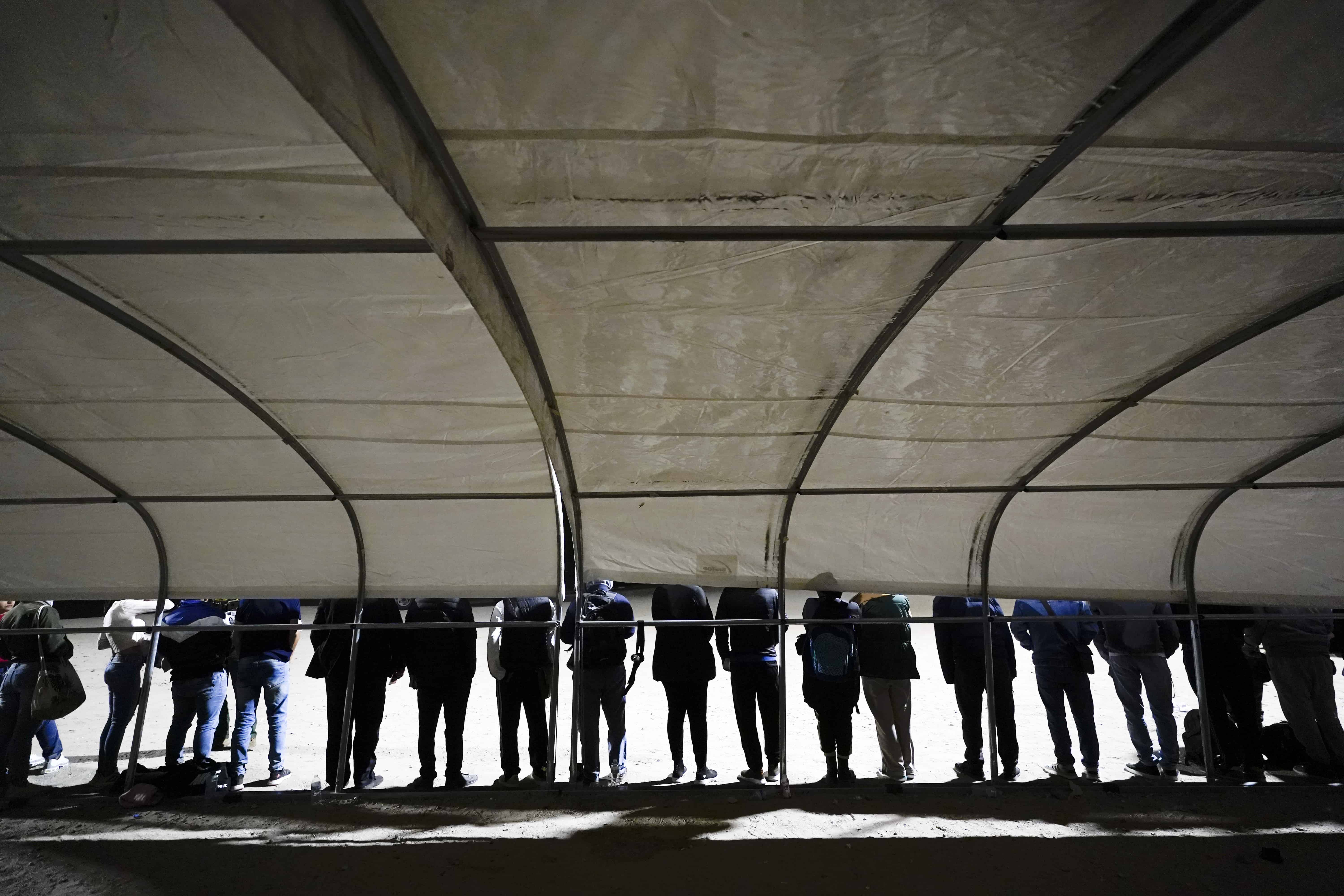 ARCHIVO - Un grupo de migrantes, en su mayoría de Cuba y República Dominicana, espera después de cruzar la frontera desde México y entregarse a las autoridades para solicitar asilo cerca de Yuma, Arizona, el 3 de noviembre de 2022.<br>