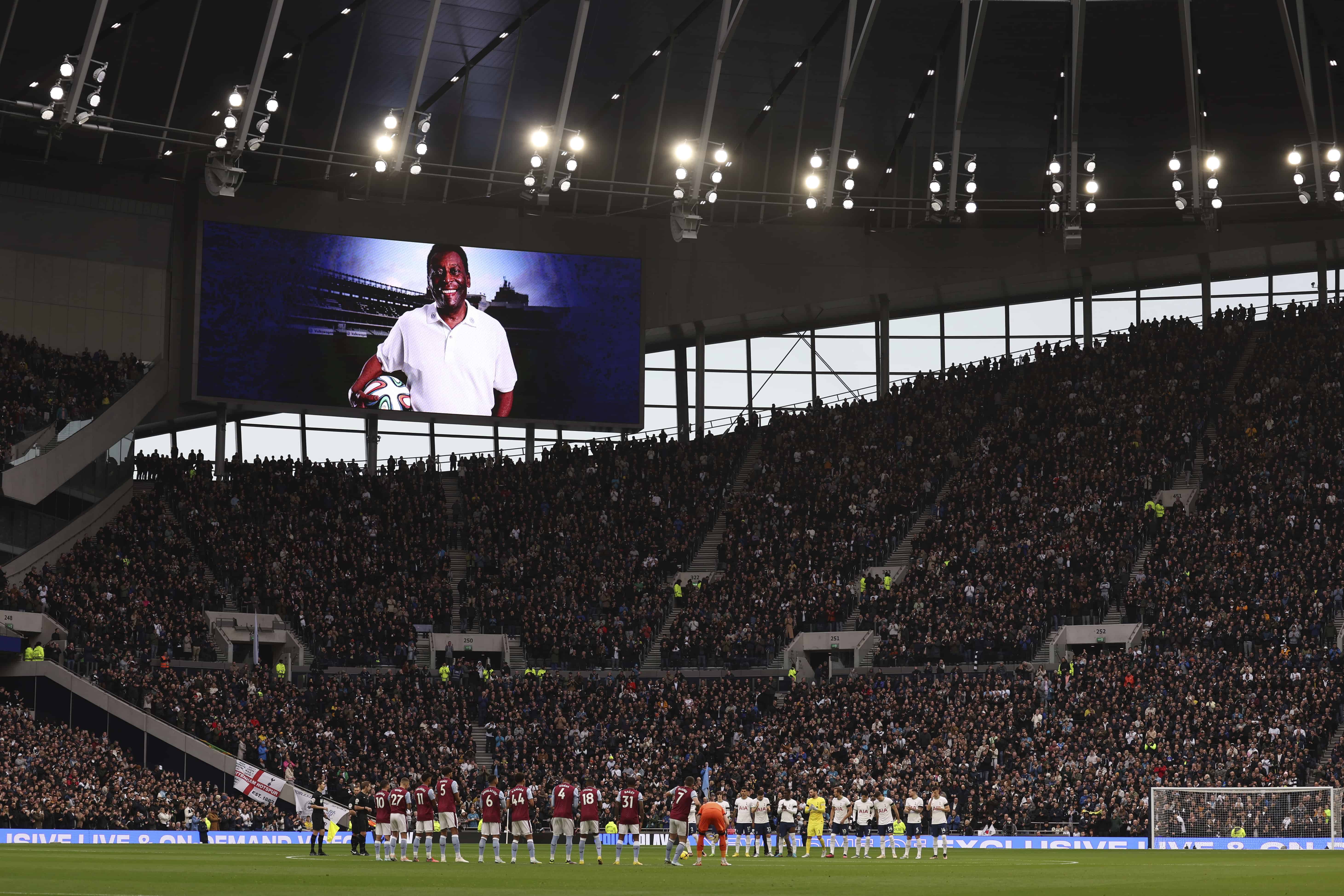 Los jugadores hacen fila mientras una imagen de la leyenda del fútbol Pelé se muestra en una pantalla gigante antes del partido de fútbol de la Liga Premier inglesa entre Tottenham Hotspur y Aston Villa en el estadio Tottenham Hotspur de Londres, el domingo 1 de enero de 2023. 