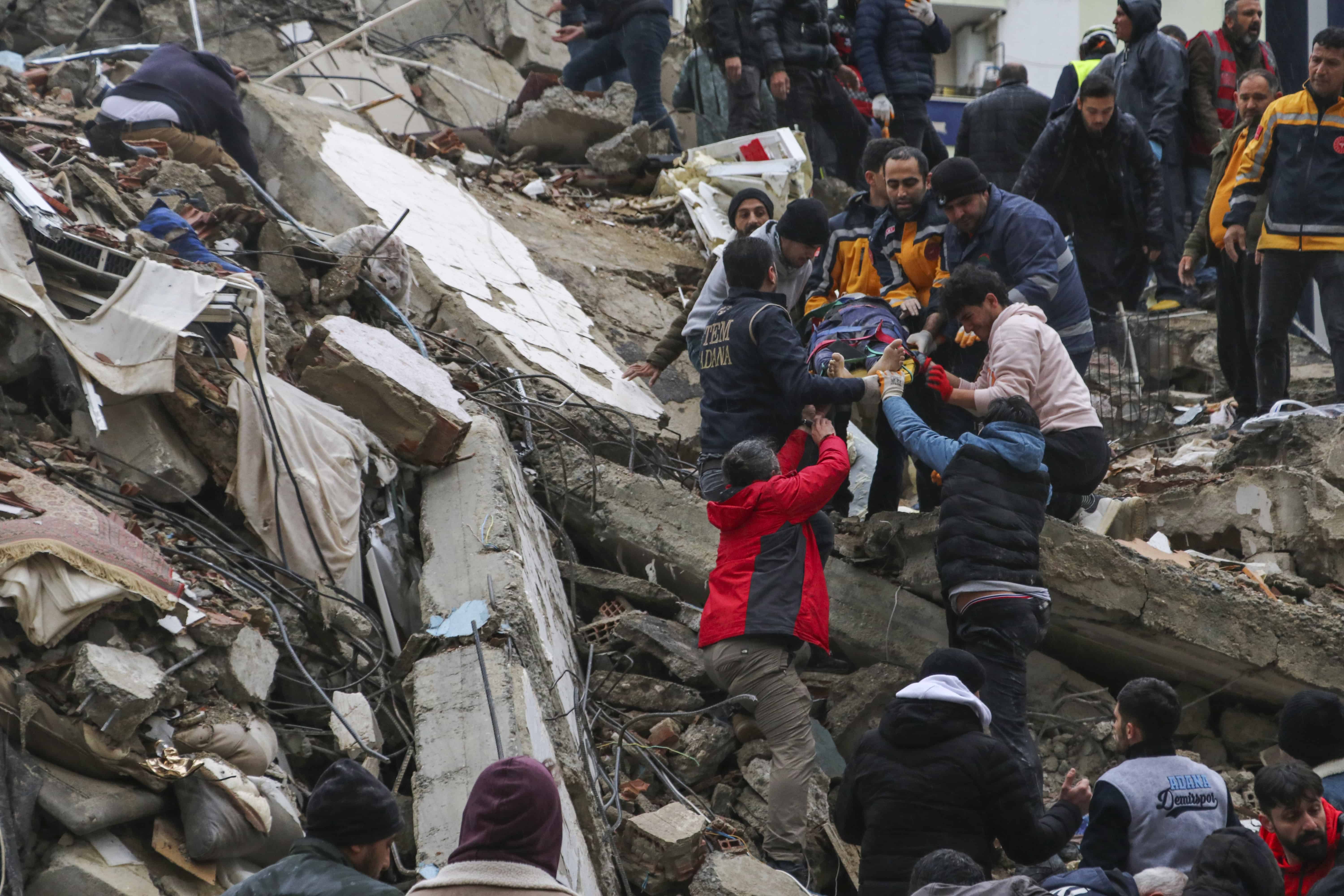 Personas y equipos de emergencia rescatan a una persona en una camilla de un edificio derrumbado en Adana, Turquía, el lunes 6 de febrero de 2023. Un poderoso terremoto derribó varios edificios en el sureste de Turquía y Siria y se temen muchas víctimas.