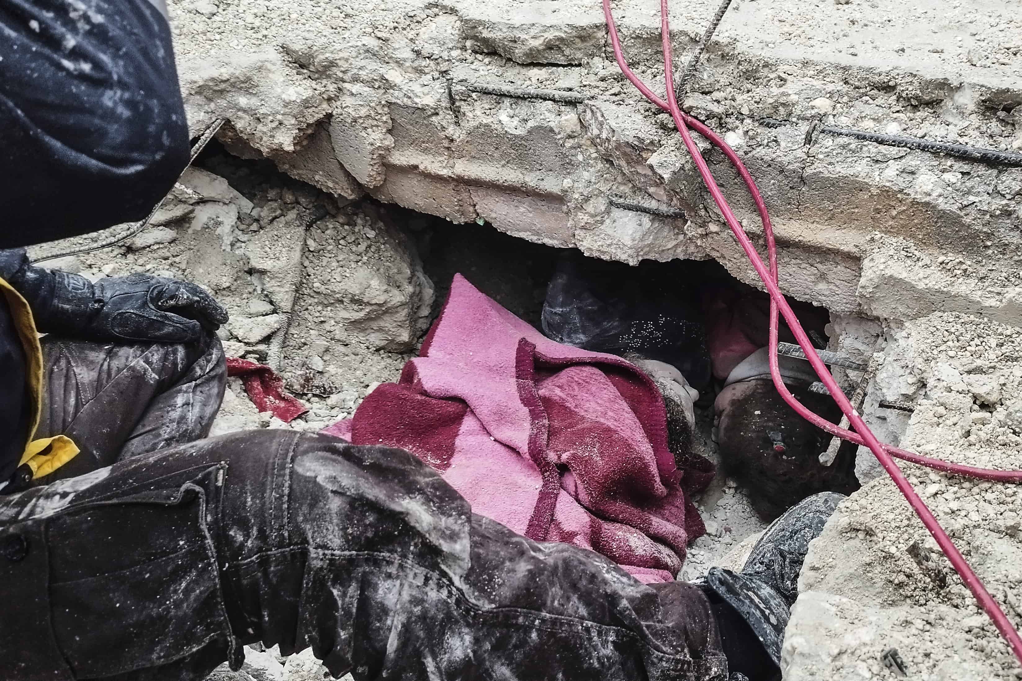 Miembros de la defensa civil siria buscan personas bajo los escombros de un edificio destruido en Afrin, Siria, el lunes 6 de febrero de 2023. Un poderoso terremoto golpeó el sureste de Turquía y Siria el lunes temprano, derribando edificios y enviando a los residentes en pánico a salir en un frío invierno. noche.