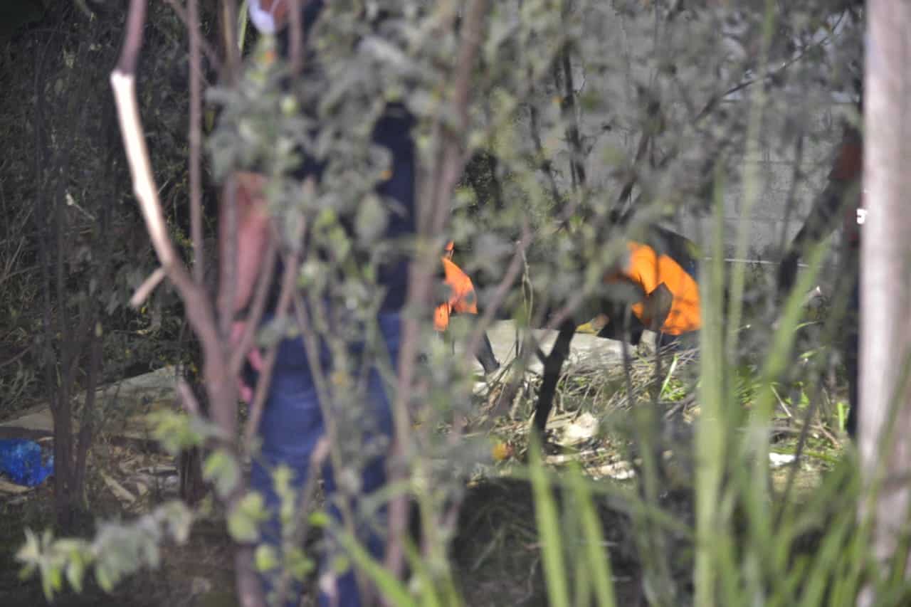 Hombre de la Defensa Civil tapan el hoyo donde fueron hallados los cadáveres.