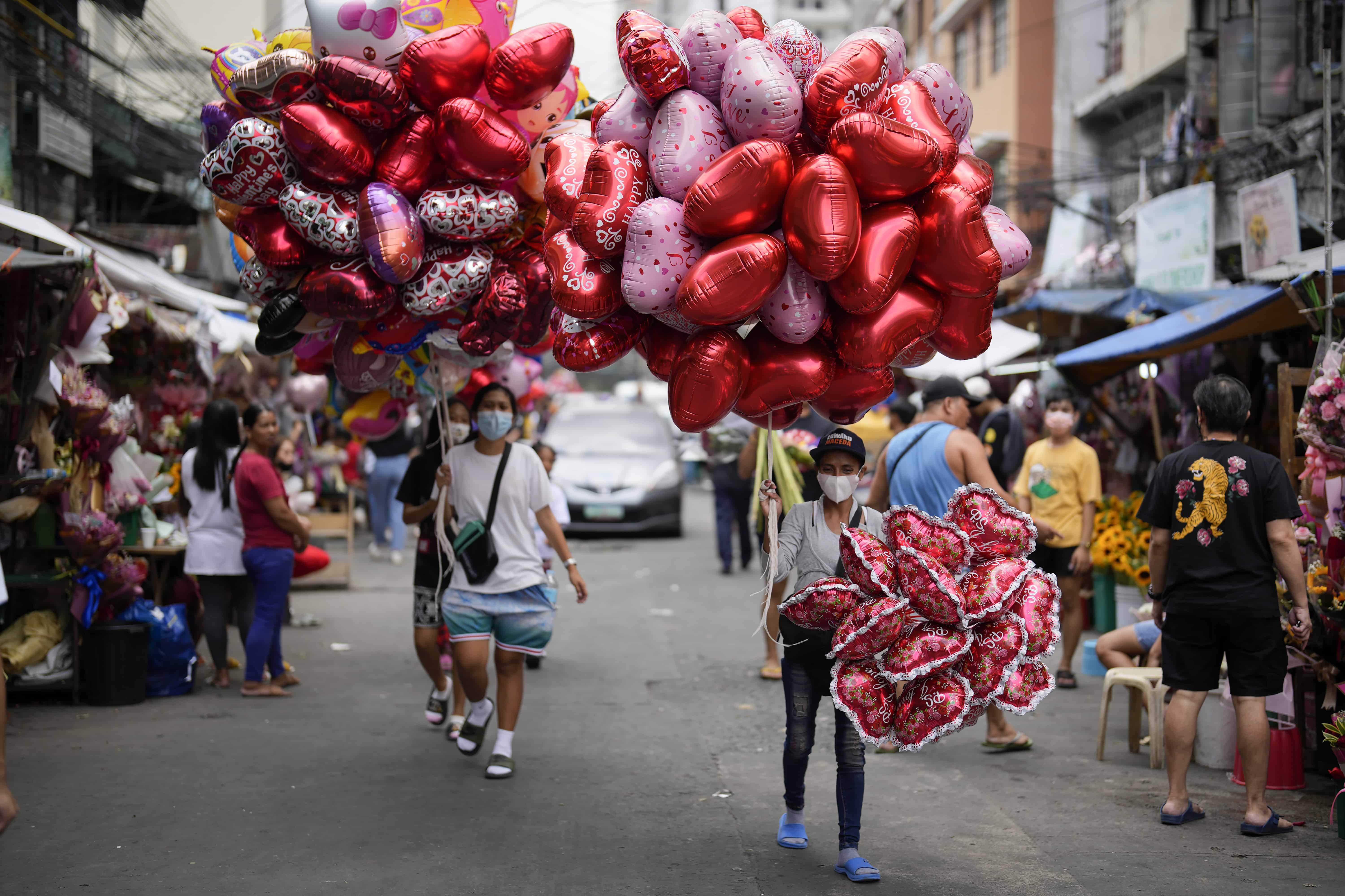 Mujeres venden globos con forma de corazón en un mercado de flores en Manila, Filipinas, el lunes 13 de febrero de 2023. Los precios de las flores han aumentado debido a la gran demanda un día antes del Día de San Valentín.