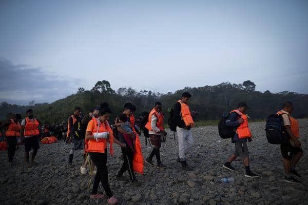 Un grupo de migrantes con chalecos salvavidas esperan para ser trasladados en canoa desde la Quebrada León hasta a la comunidad de Bajo Chiquito