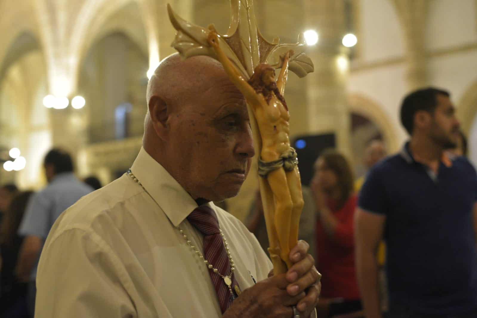 Un miembro de la iglesia lleva la escultura de Jesús crucificado.