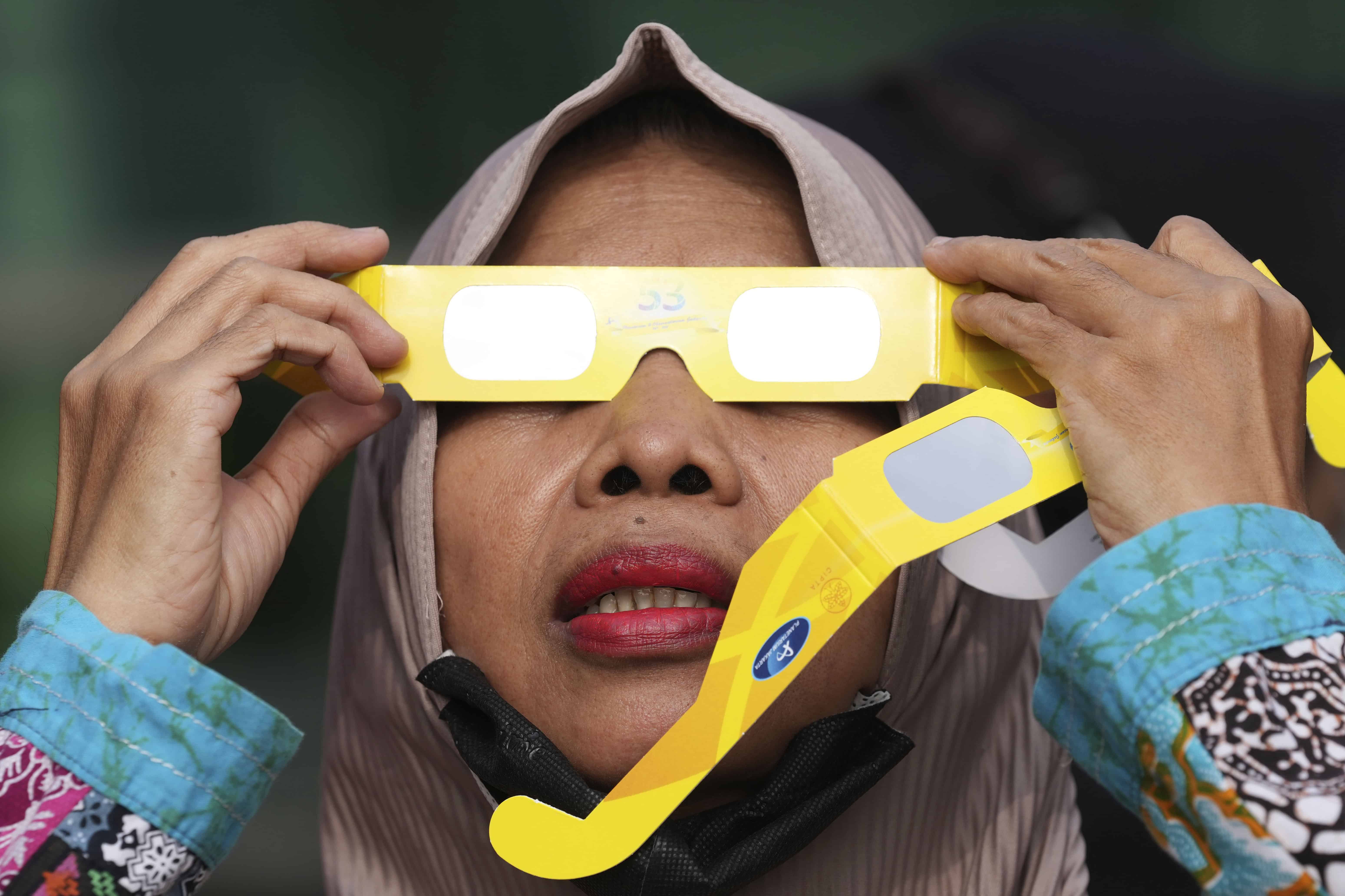 Una mujer utiliza gafas protectoras para ver un eclipse solar en Yakarta, Indonesia, el jueves 20 de abril de 2023. Los pocos afortunados en su ruta o bien vieron la oscuridad de un eclipse total o el “anillo de fuego” cuando el sol asomaba tras la Luna. 