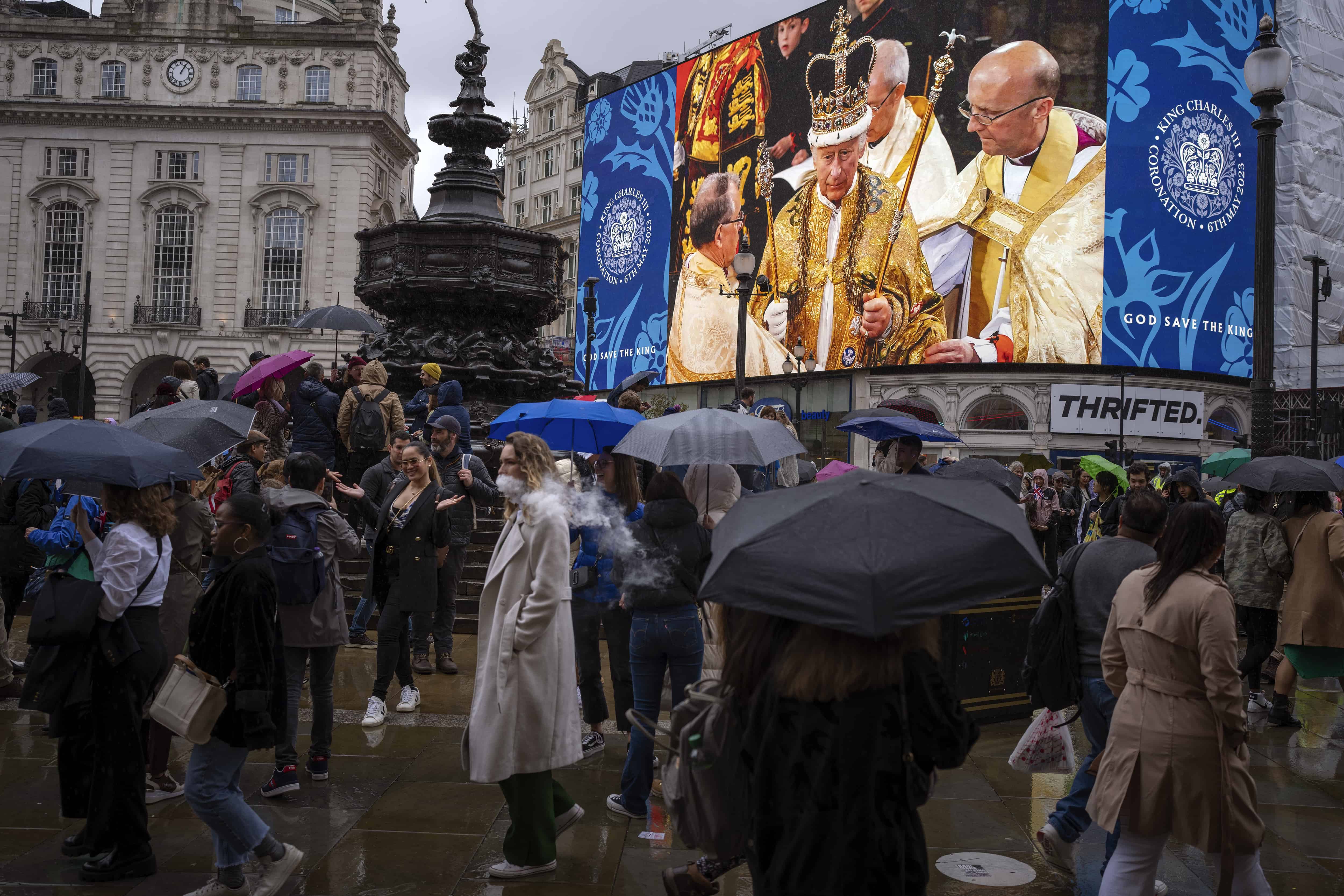La gente pasa frente a una pantalla gigante en Piccadilly Circus, en el centro de Londres, que muestra una imagen del rey Carlos III de Gran Bretaña durante la ceremonia de coronación en la Abadía de Westminster, el sábado 6 de mayo de 2023.