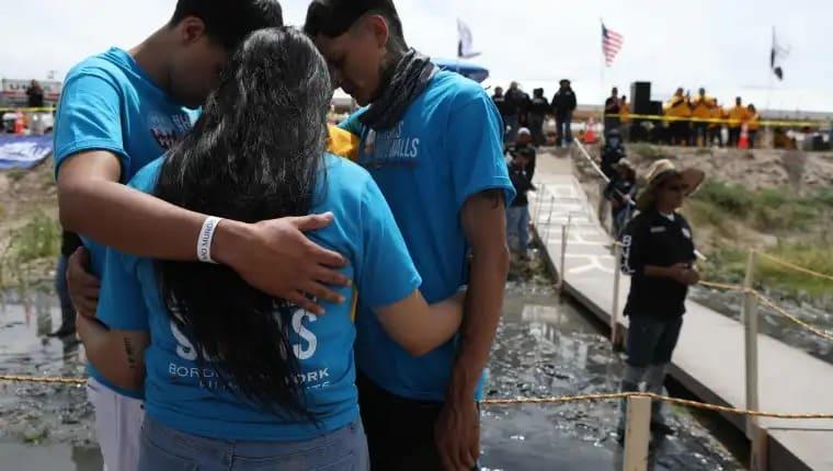 Migrantes se abrazan y derriban simbólicamente el muro entre México y EEUU
