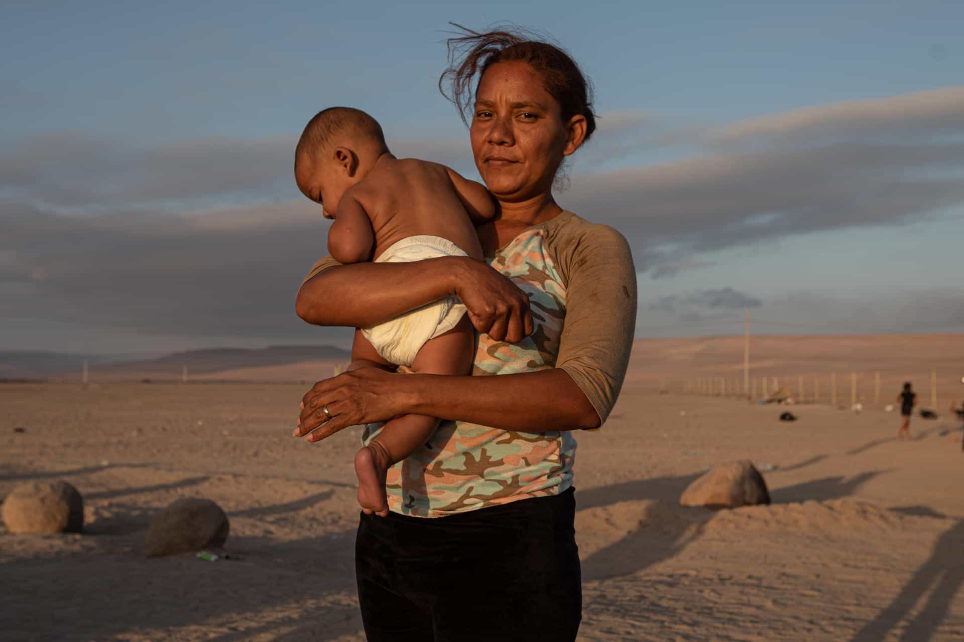 Jimir Coromoto (51), sostiene a su hijo mientras esperan soluciones a su situación migratoria, el 3 de mayo de 2023, en el paso fronterizo Chacalluta, en Arica (Chile).