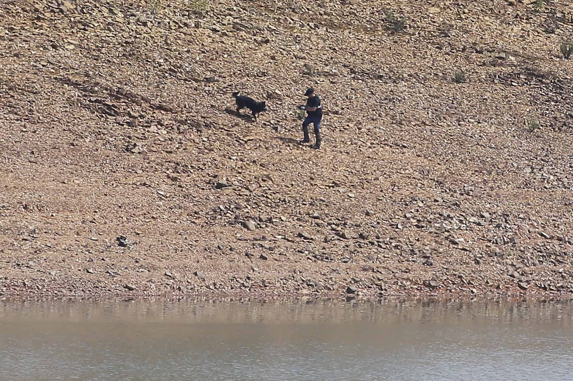 Un oficial de policía y un perro trabajan en la represa de Arade cerca de Silves, Portugal, el martes 23 de mayo de 2023.