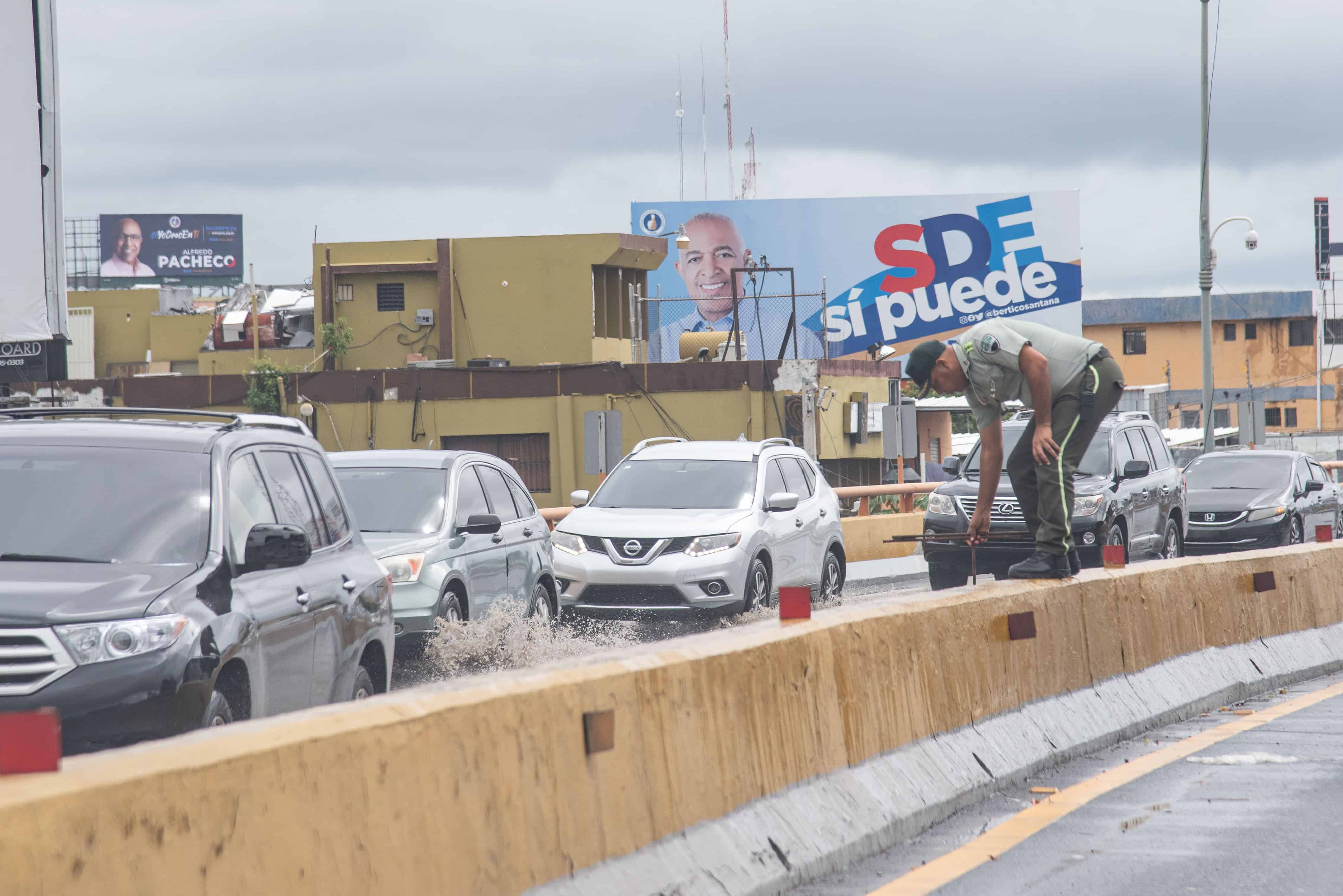 Un agente de Digesett trata de destapar un desague del elevado 27 de Febrero. El tapón llegaba hasta la autopista Coronel Fernández Domínguez en Santo Domingo Este.