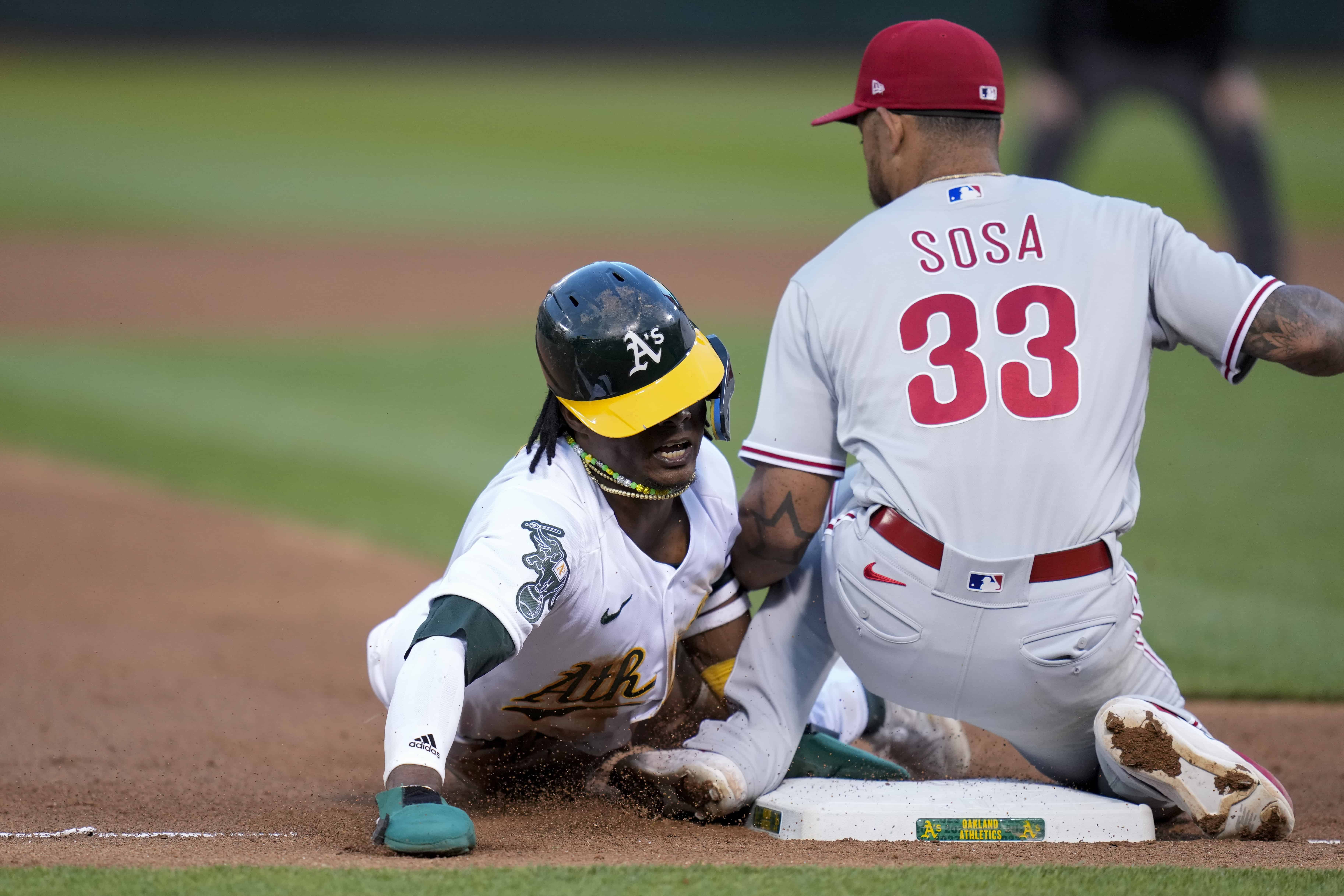 Esteury Ruiz, de los Atléticos de Oakland, roba la tercera base junto al tercera base de los Filis de Filadelfia, Edmundo Sosa (33), durante la sexta entrada de un partido de béisbol en Oakland, California, el viernes 16 de junio de 2023.