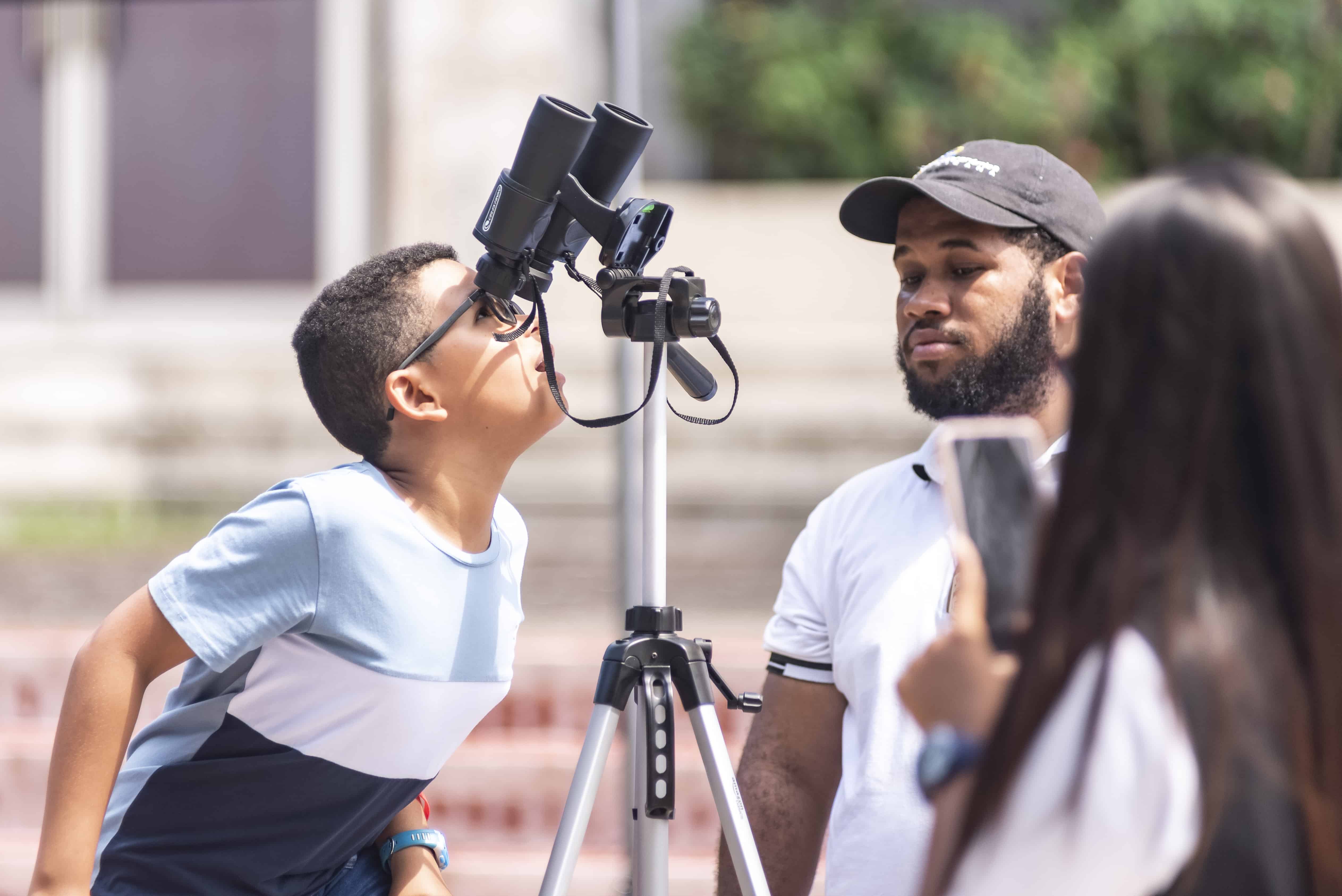 Un niño observa a través de prismaticos especializados el Sol.