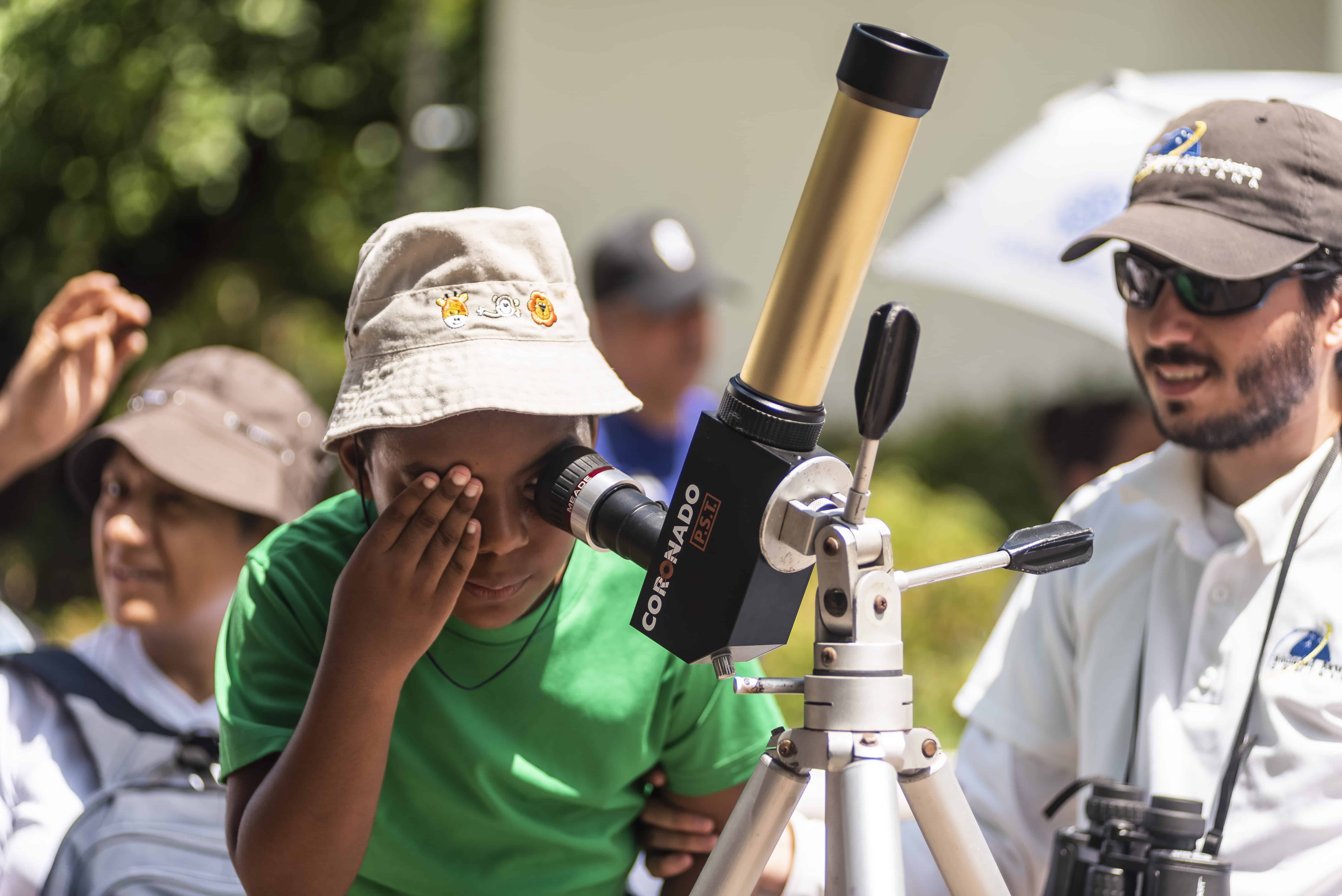 Samuel Santana ayuda a un niño a observar con un telescopio tipo coronado