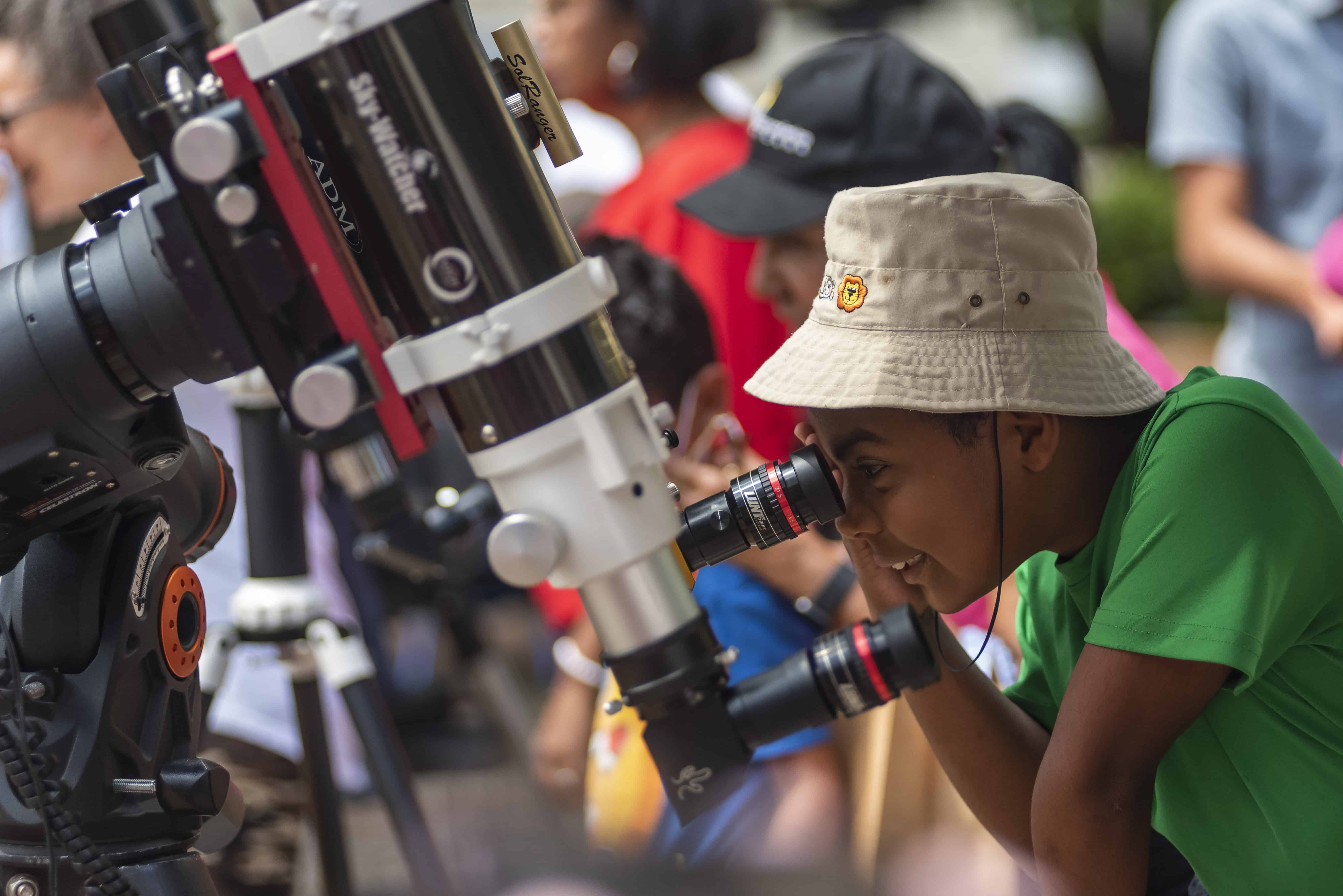 Samuel Santana ayuda a un niño a observar con un telescopio tipo coronado