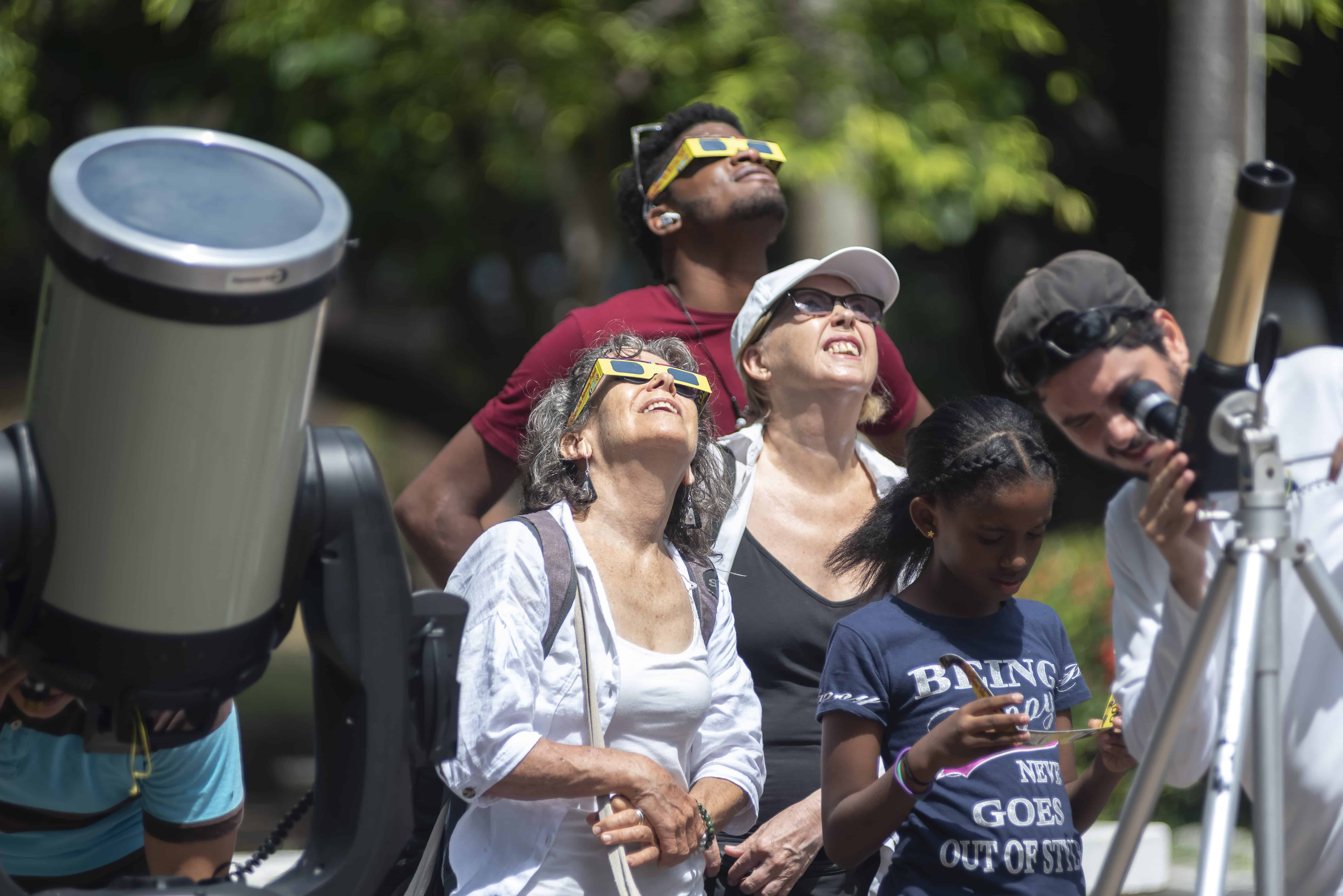 Las personas realizan la actividad con entusiasmo al mirar por los diversos telescopios