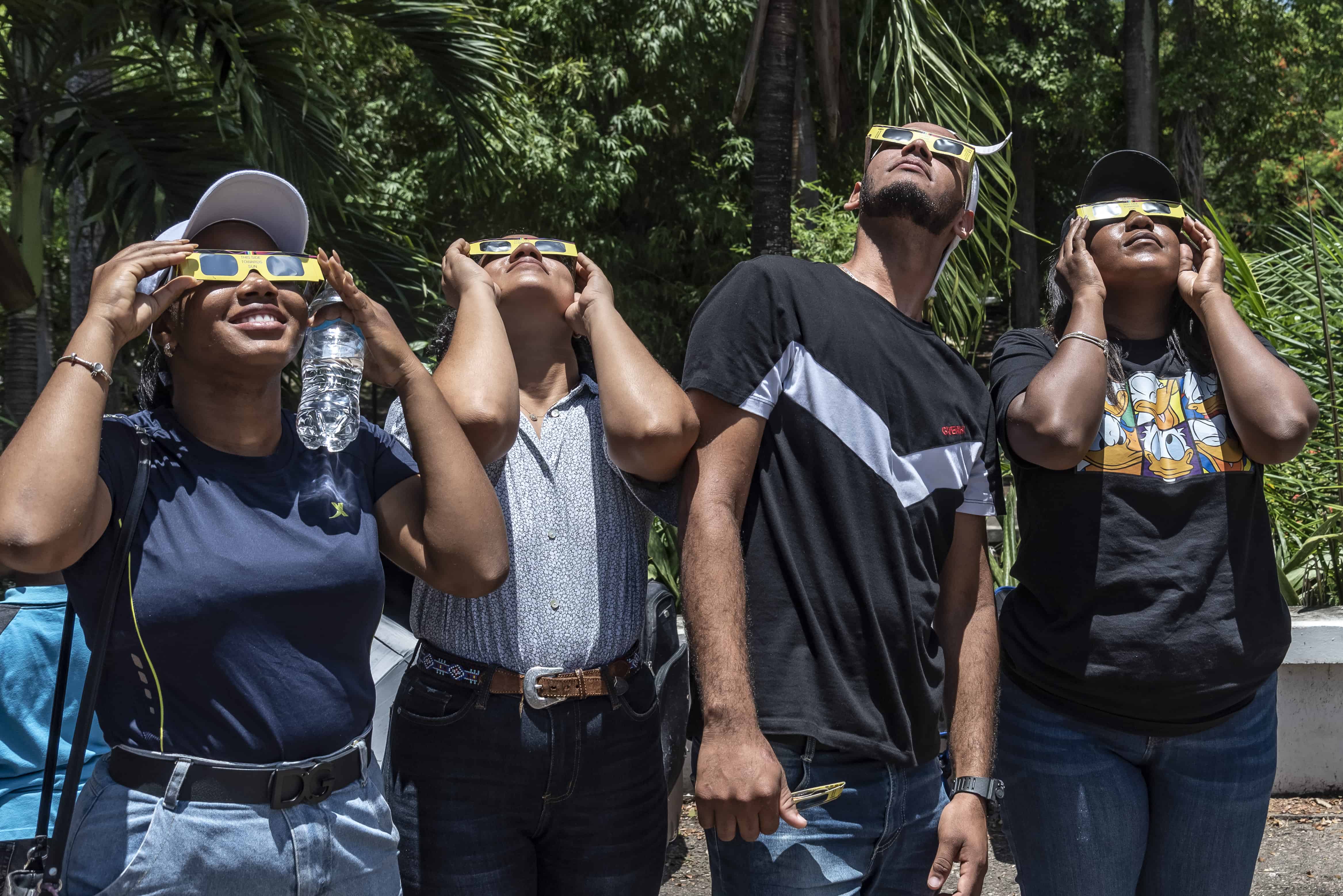 Un grupo de jovenes observan el sol con los lentes